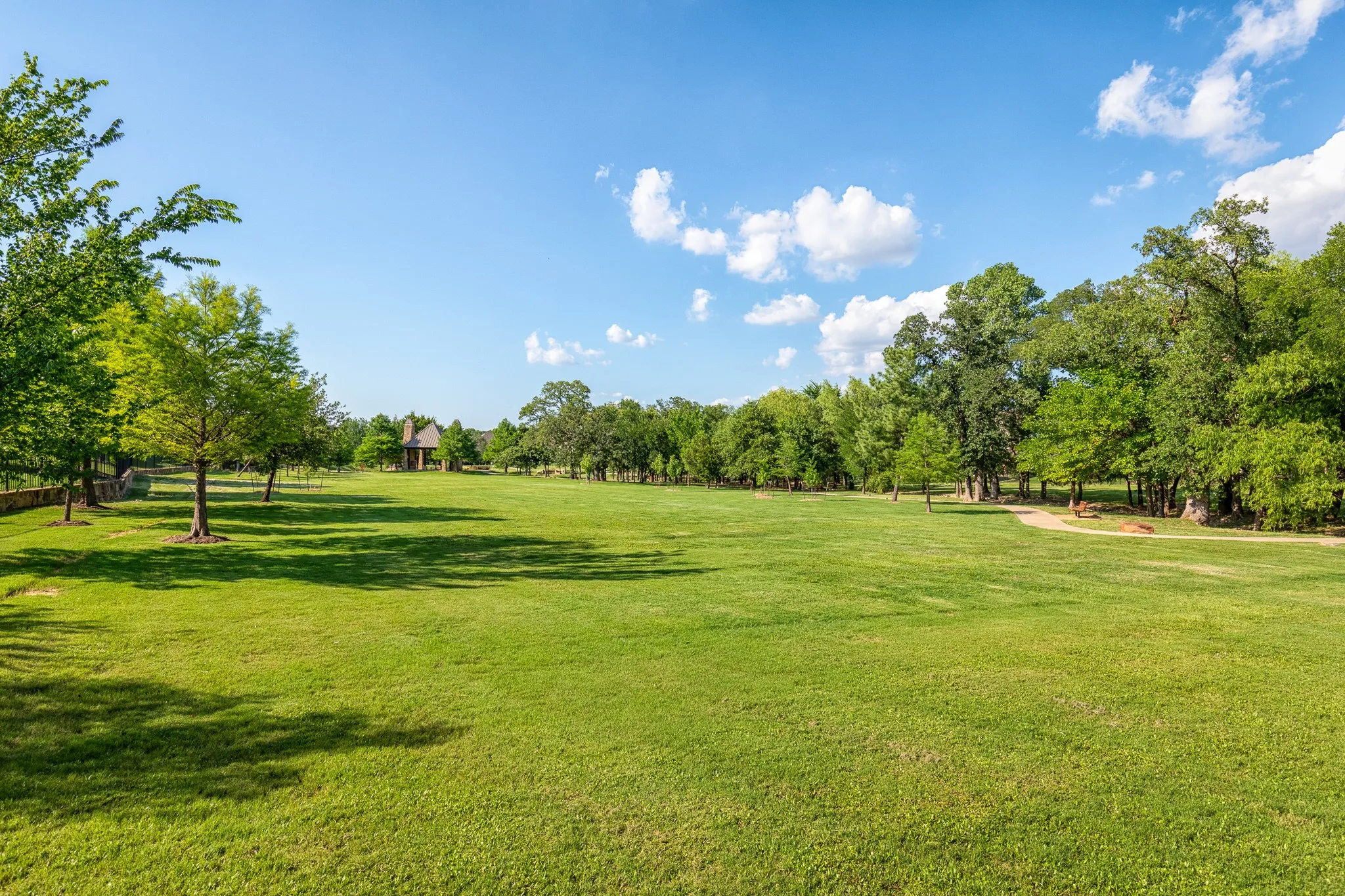 Expansive green space with mature trees, a meandering path