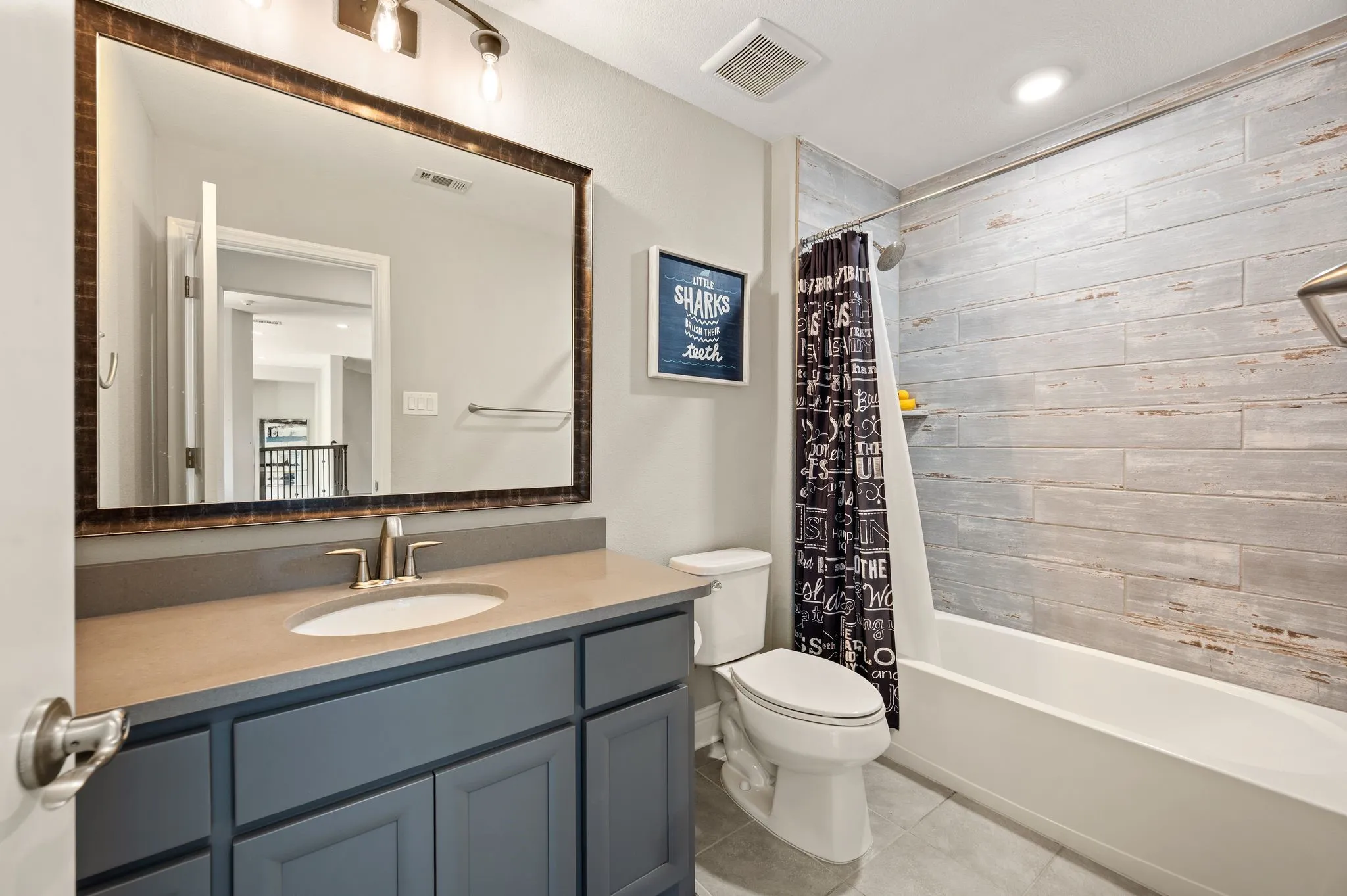 Spa-inspired bathroom featuring a custom navy vanity with dual-sink configuration, polished countertop, and framed mirror