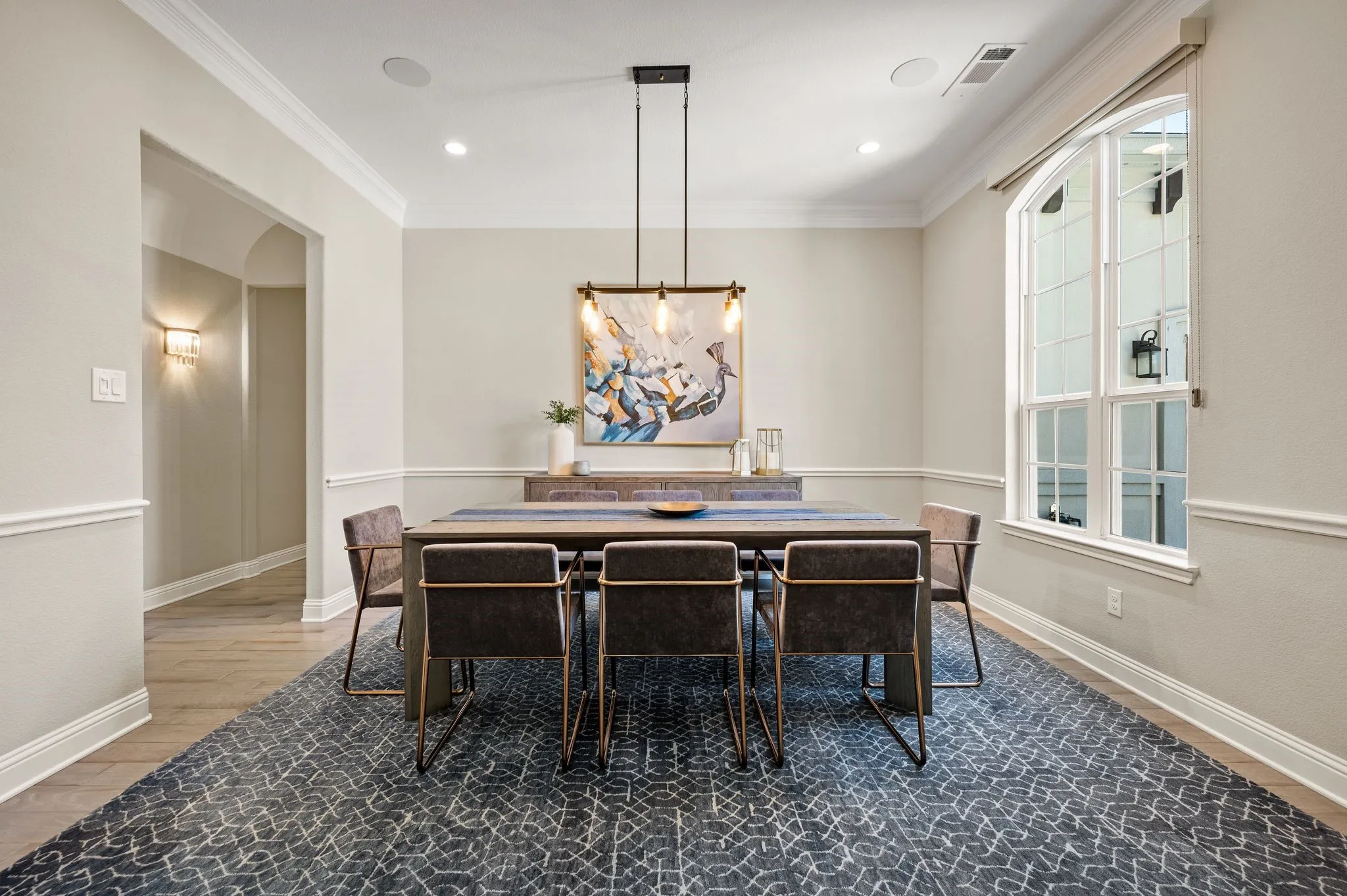 Elegant dining room featuring hardwood flooring, crown molding, and wainscoting throughout