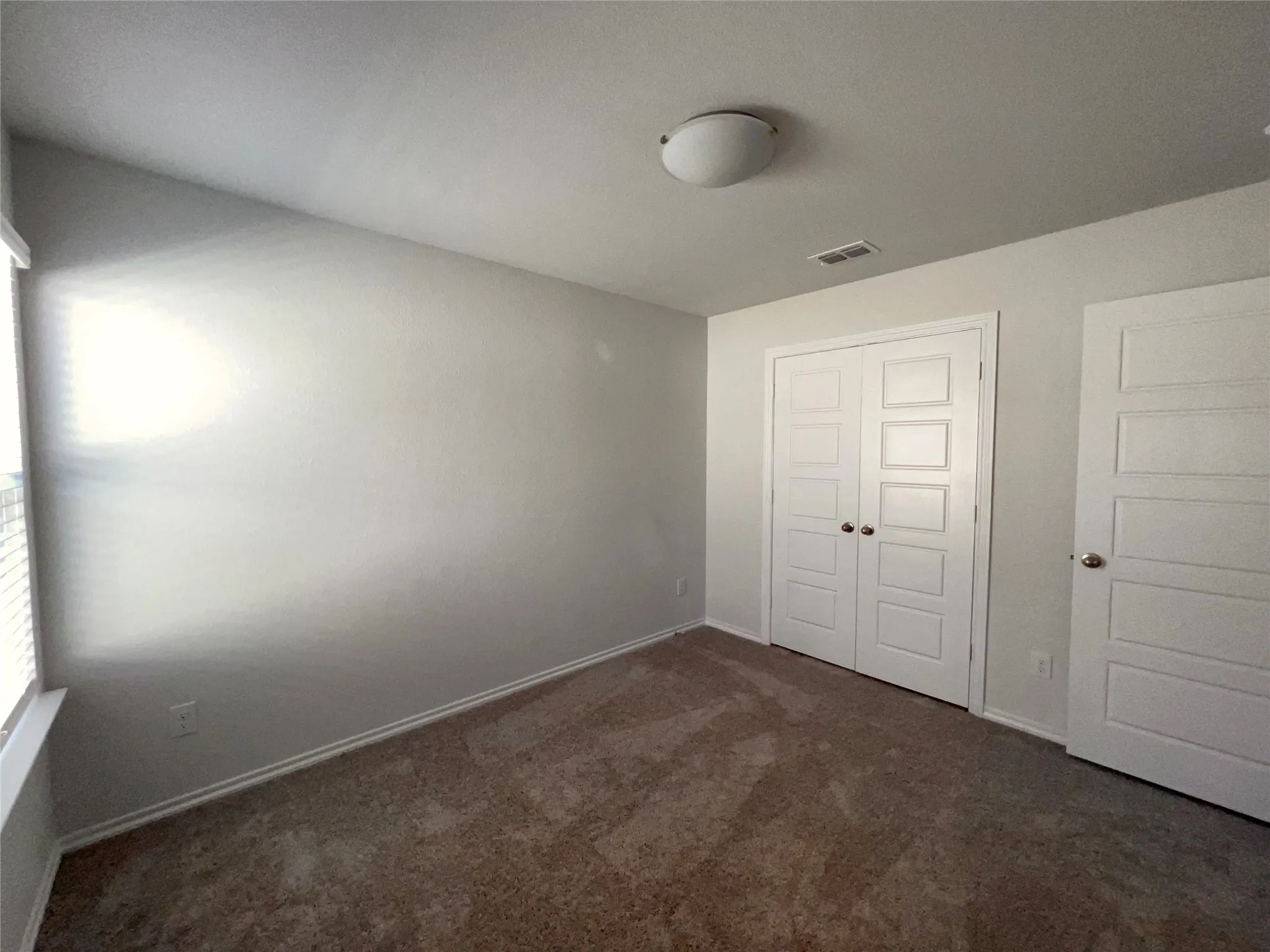 Middle bedroom view towards closet and door.