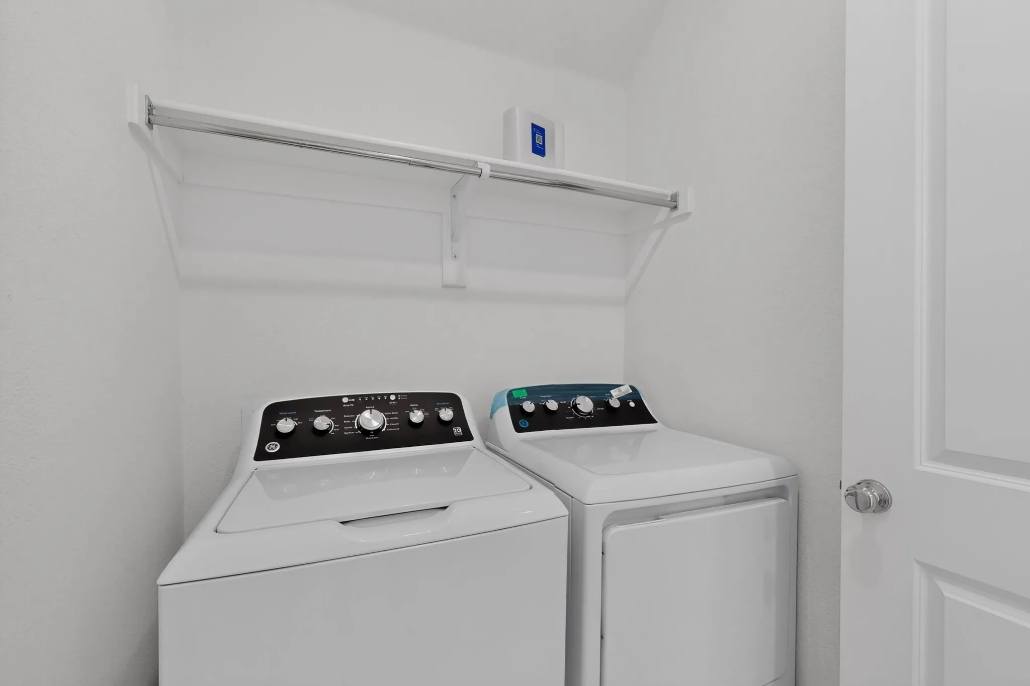 Dedicated laundry area with a white shelving unit and hanging rod