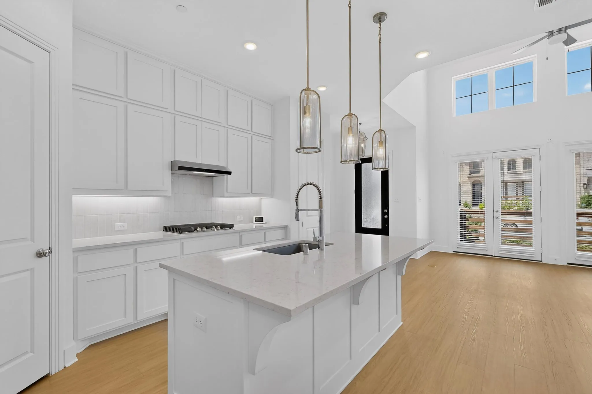 Kitchen with white cabinetry, stainless steel gas range, and a large island with a sink and pendant lighting