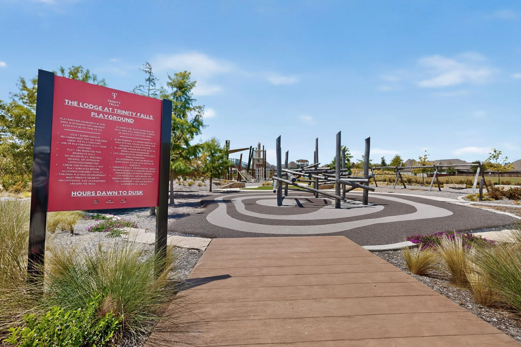 Community playground featuring a modern climbing structure, swings, and soft-surface ground cover