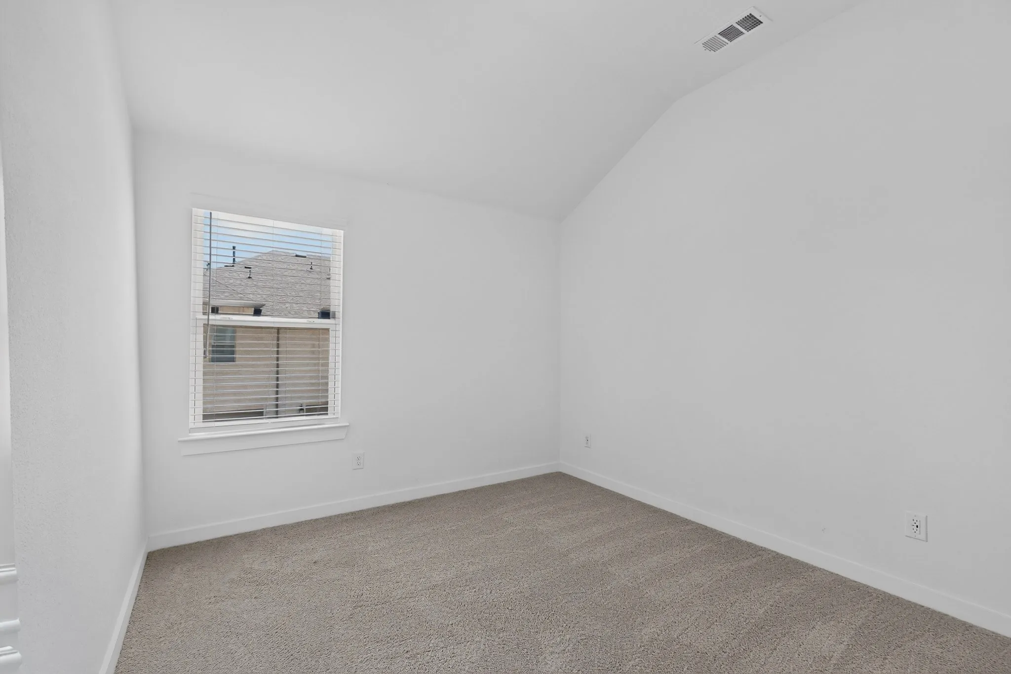 Vaulted ceiling, neutral tone walls, carpeted flooring, window with blinds, white trim