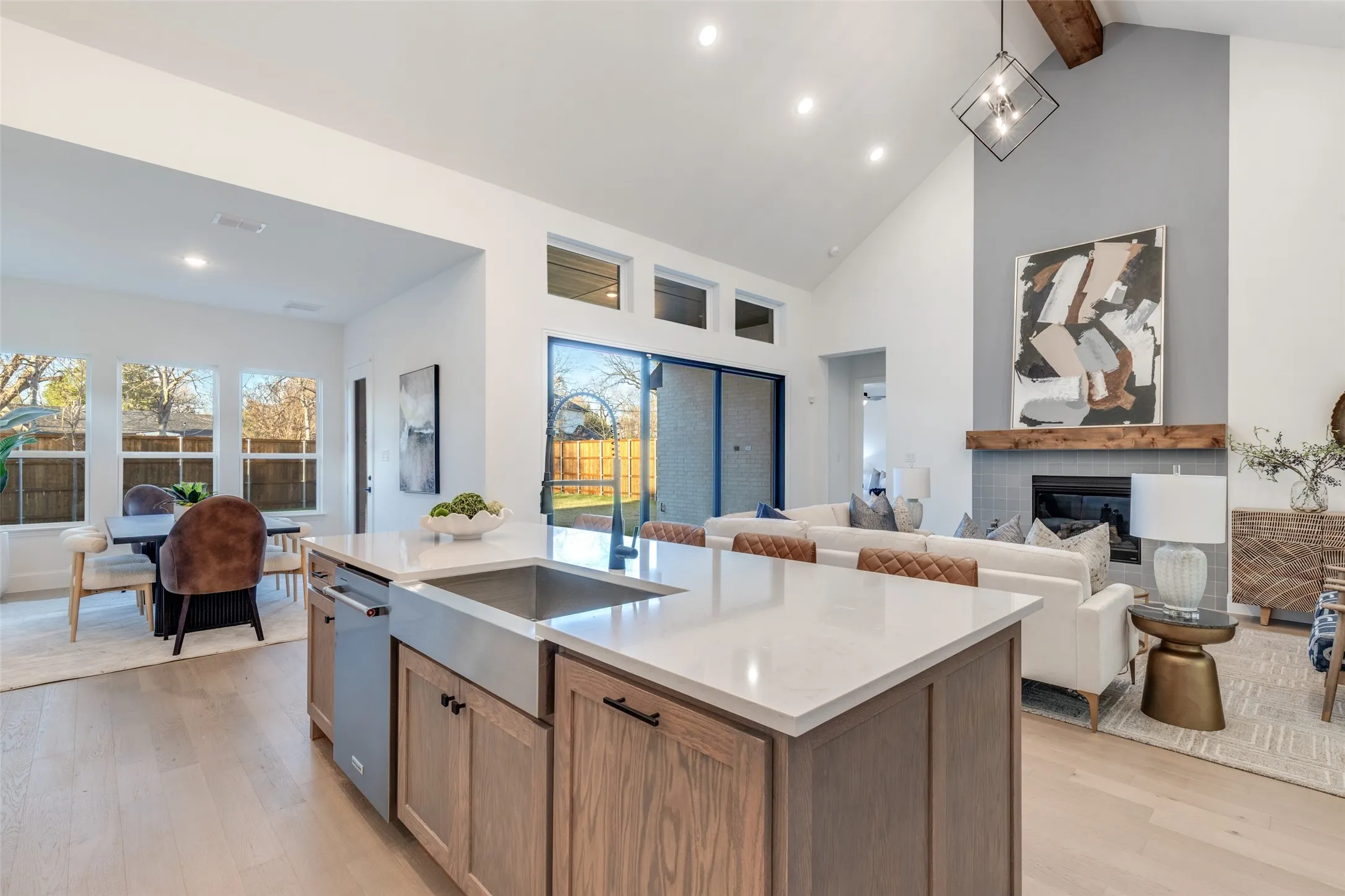 Kitchen with light wood-style floors, a glass covered fireplace, light stone countertops, brown cabinetry, and open floor plan