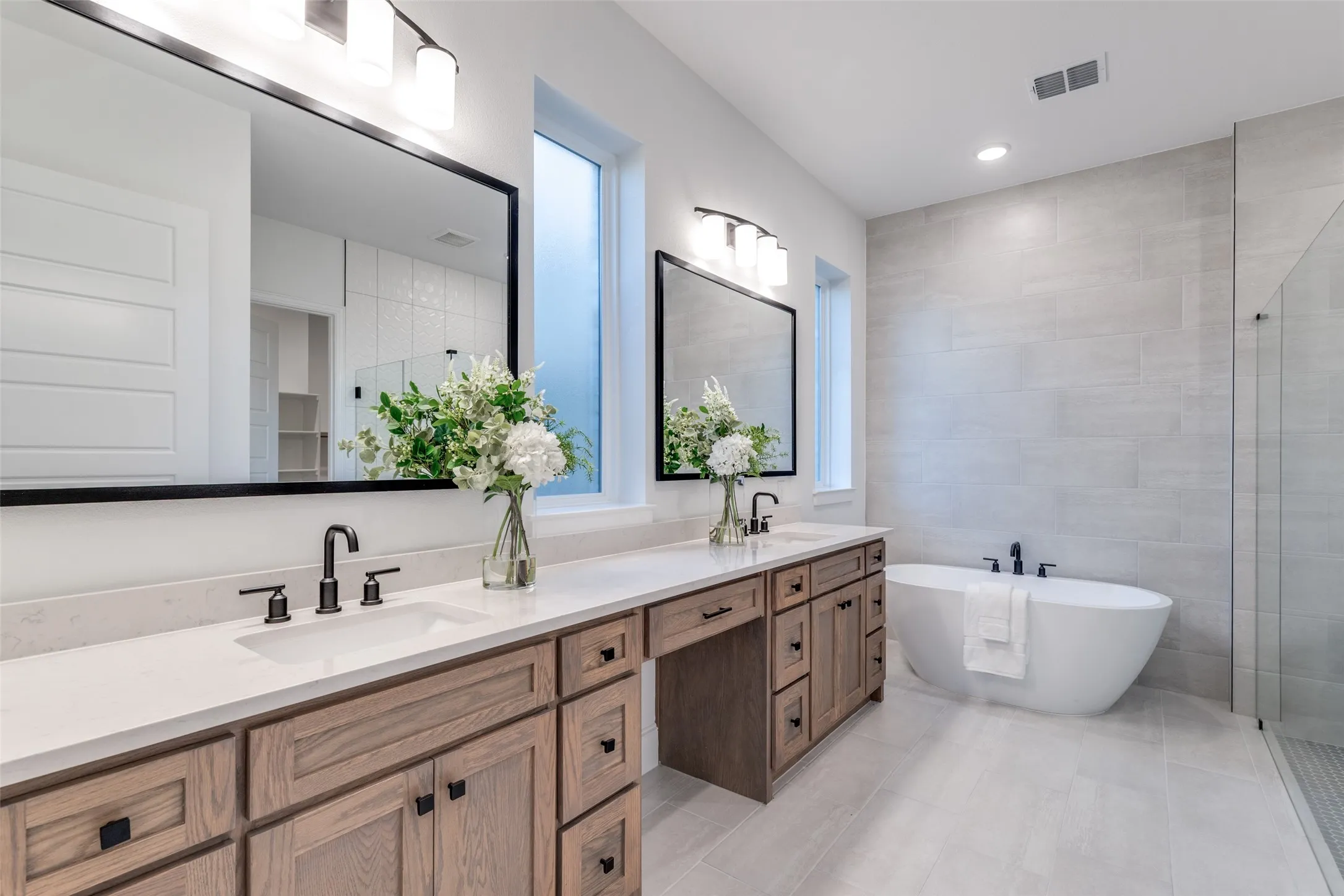 Spa-like primary bathroom with a freestanding bath, a large walk-in shower, double vanity, tile walls, and recessed lighting