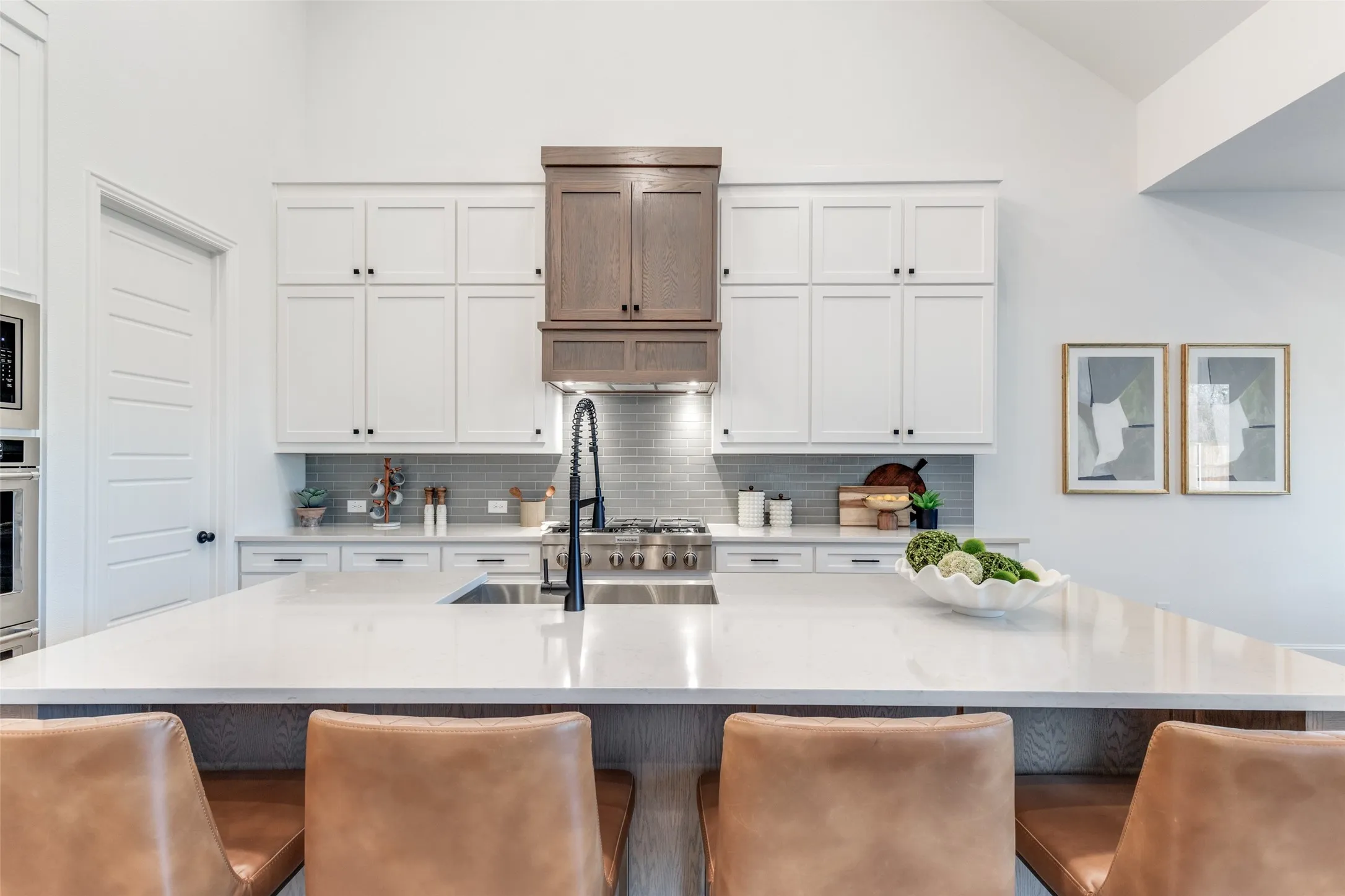 Kitchen with white cabinets, a kitchen bar, backsplash, and lofted ceiling