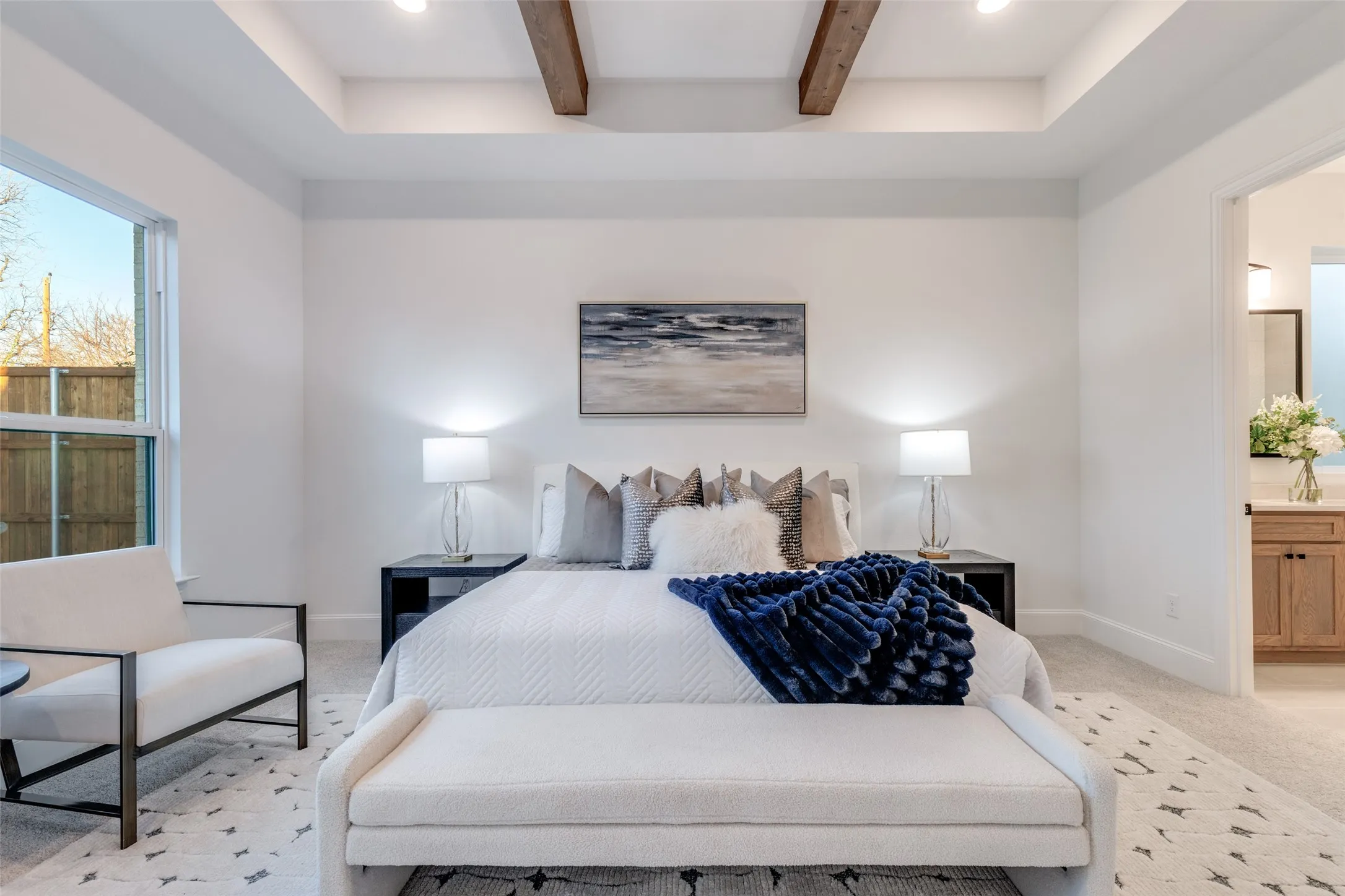Luxe primary bedroom with coffered ceiling, light carpet, and beamed ceiling.