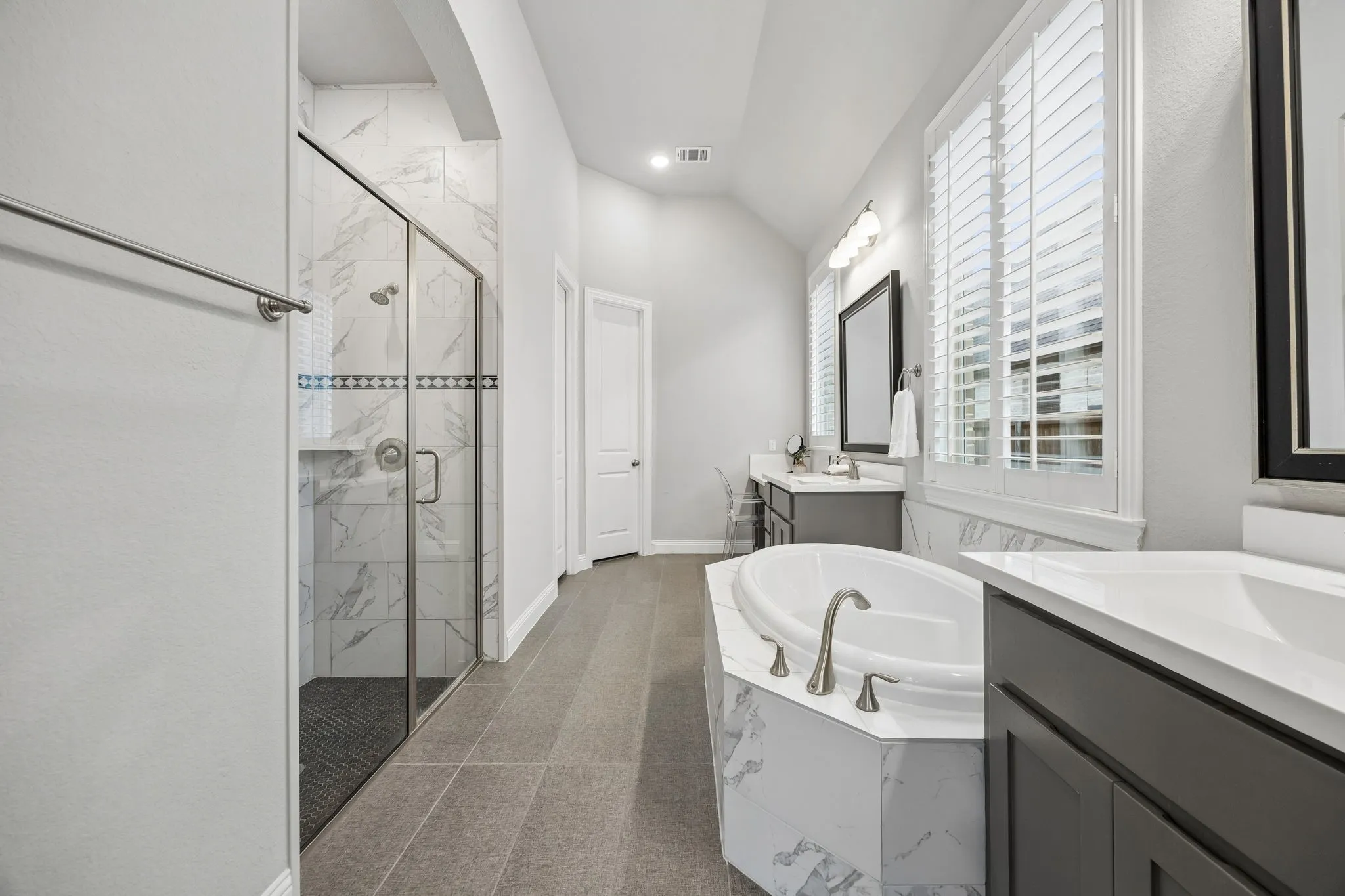 Walk-in shower with glass enclosure, separate soaking tub, and dual vanity sinks