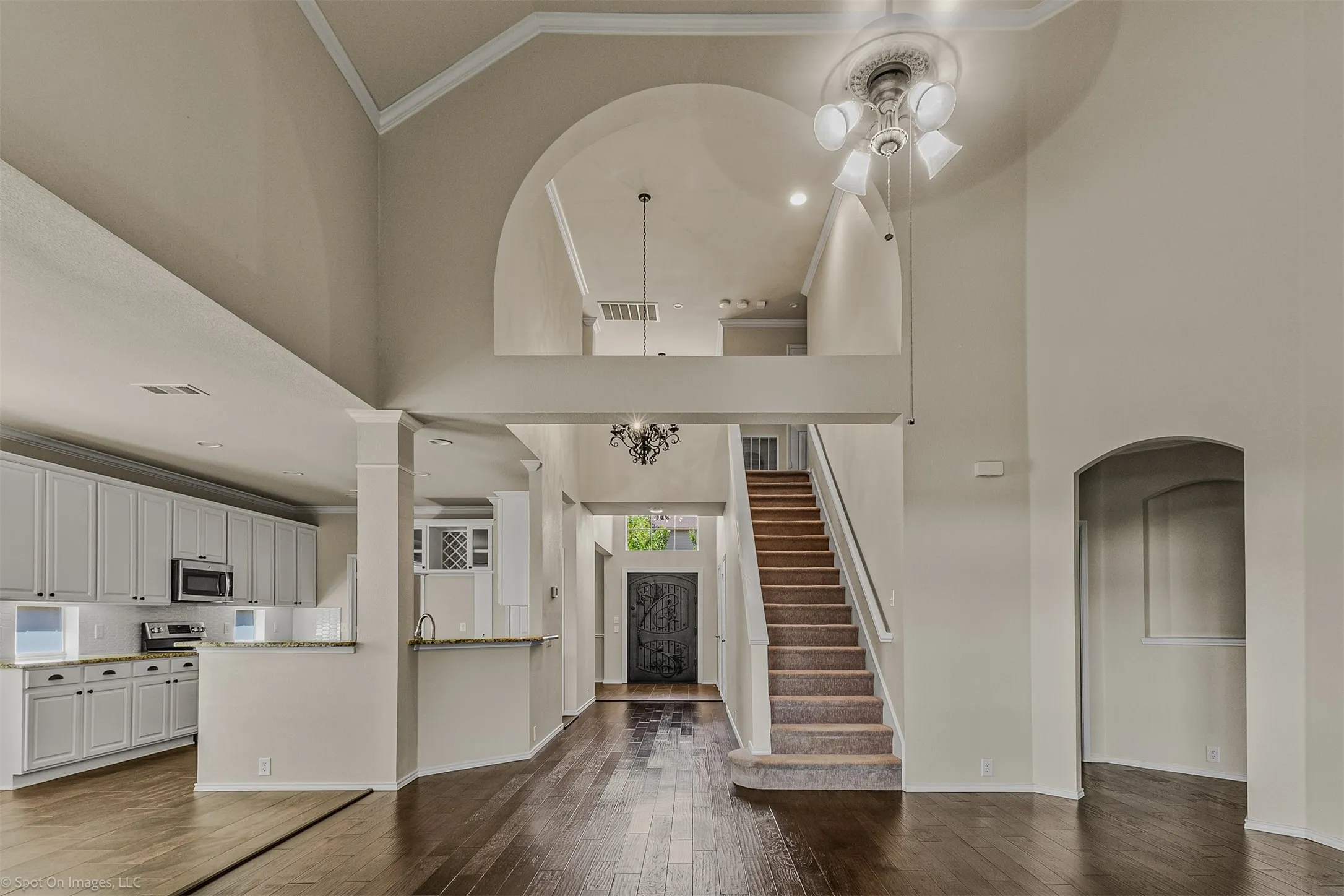 Two-story foyer with a vaulted ceiling, wood-finish flooring, and a carpeted staircase