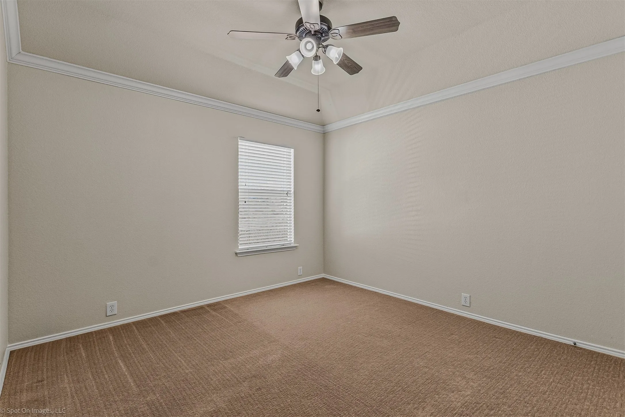 Vaulted ceiling with crown molding, ceiling fan with light fixture, window with blinds, and neutral carpeting