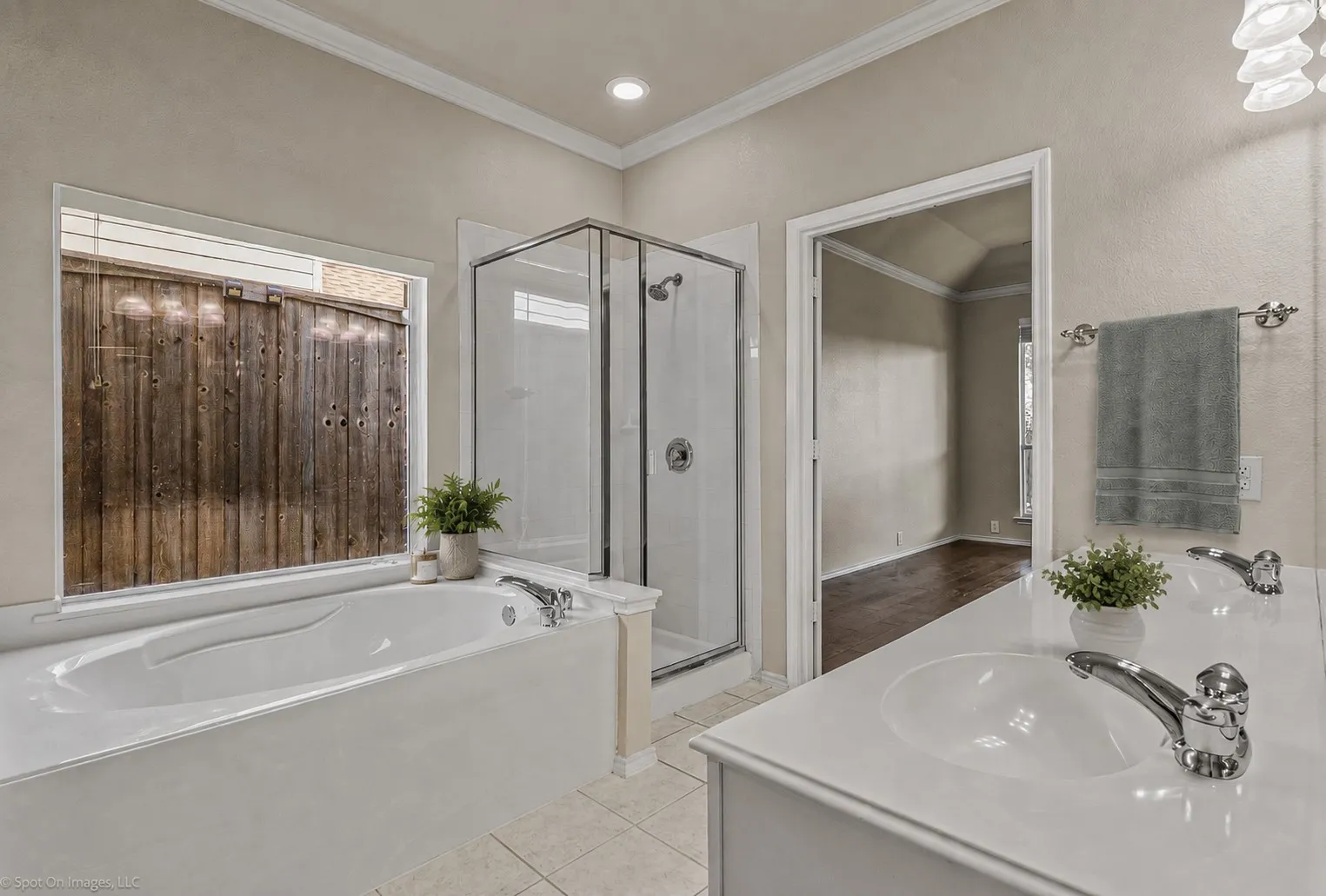 Dual vanity with integrated sinks, built-in bathtub, glass-enclosed shower, and crown molding