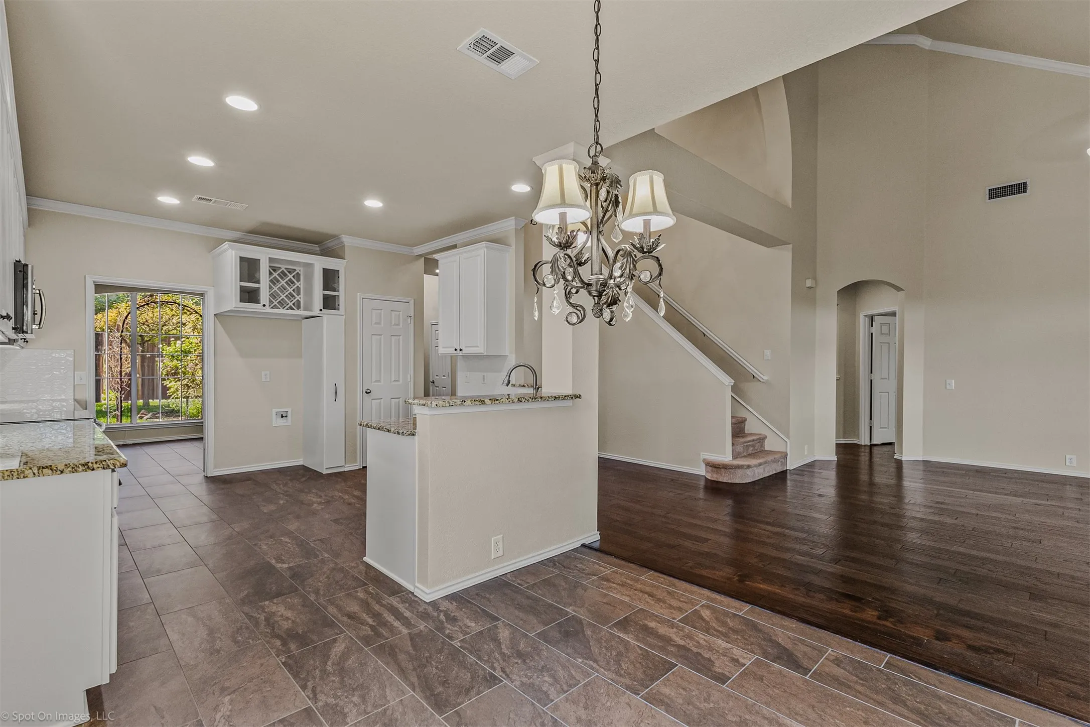 Soaring ceiling with arched details, wood-finish flooring, staircase with carpeted treads, tile flooring, and a decorative chandelier