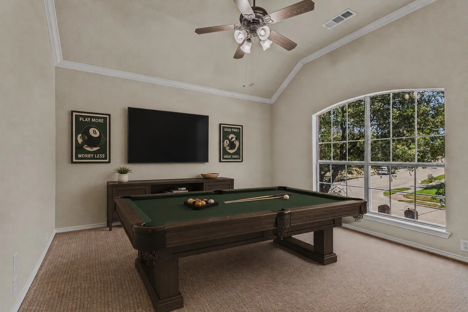 Vaulted ceiling with crown molding, ceiling fan with integrated lighting, arched multi-pane window, and neutral wall paint