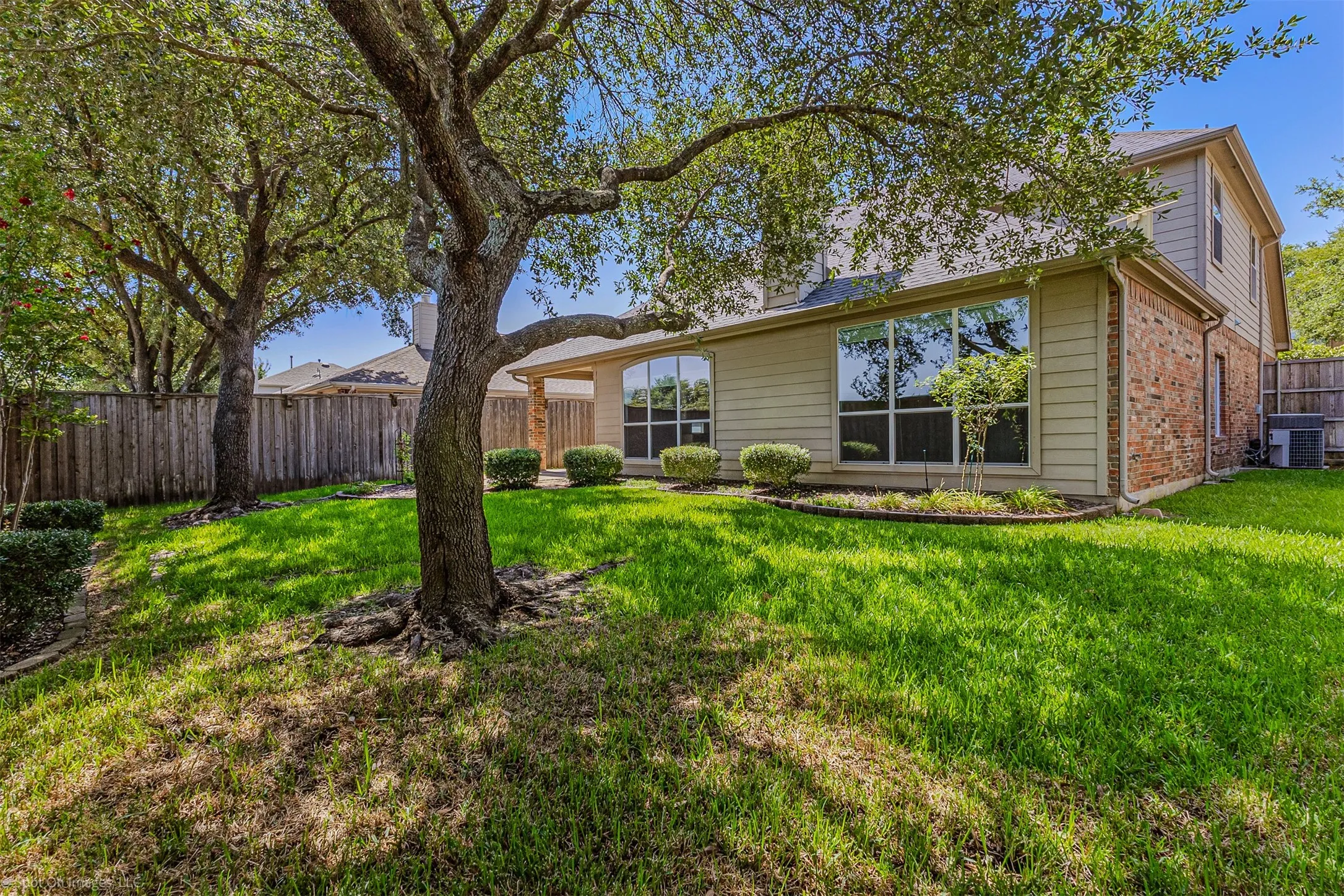 Expansive backyard featuring mature trees, a manicured lawn, and privacy fencing