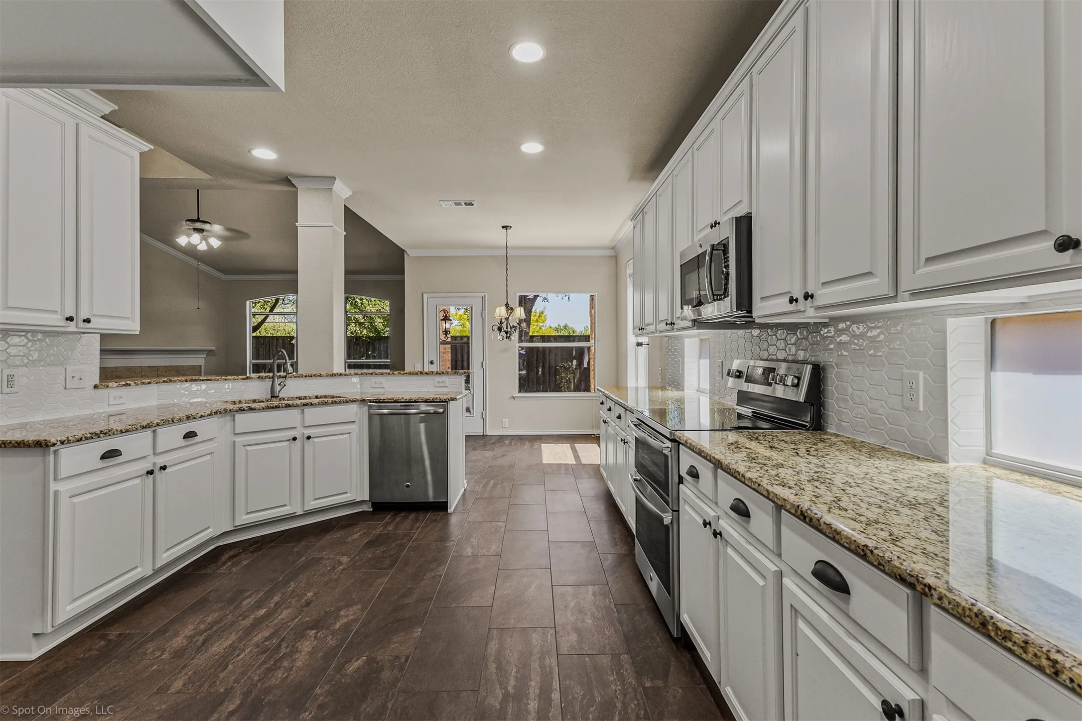 Spacious kitchen featuring white cabinetry, granite countertops, tile backsplash, stainless steel appliances, and wood-finish flooring