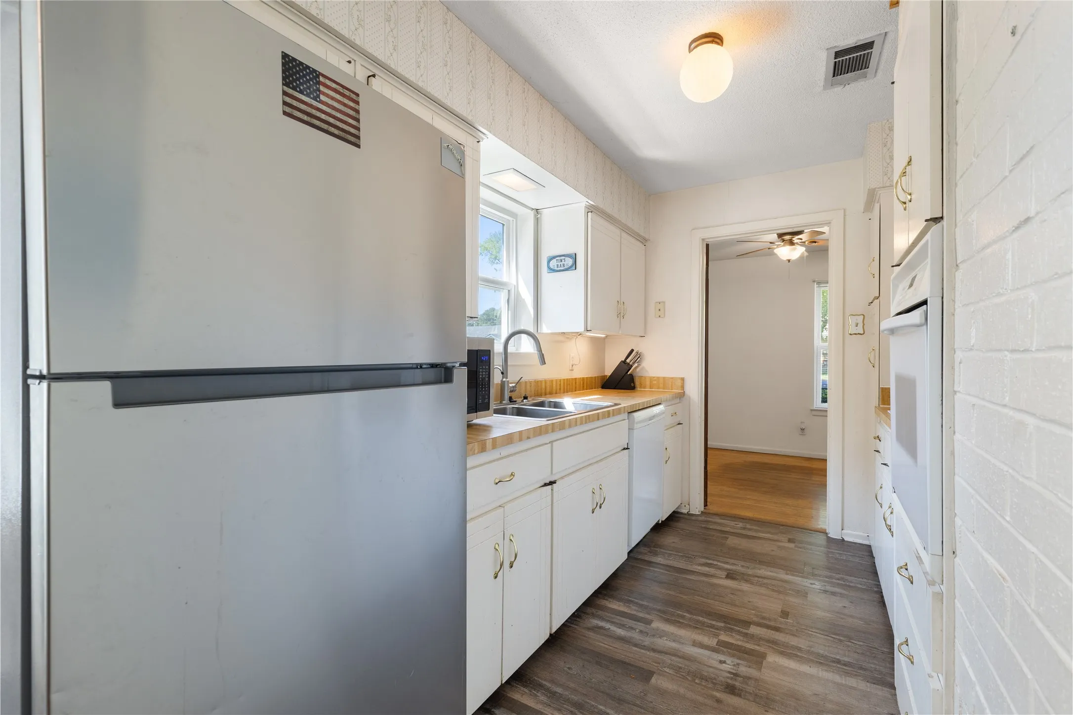 Kitchen featuring wood-finish flooring, white cabinetry, integrated sink, and built-in wall oven