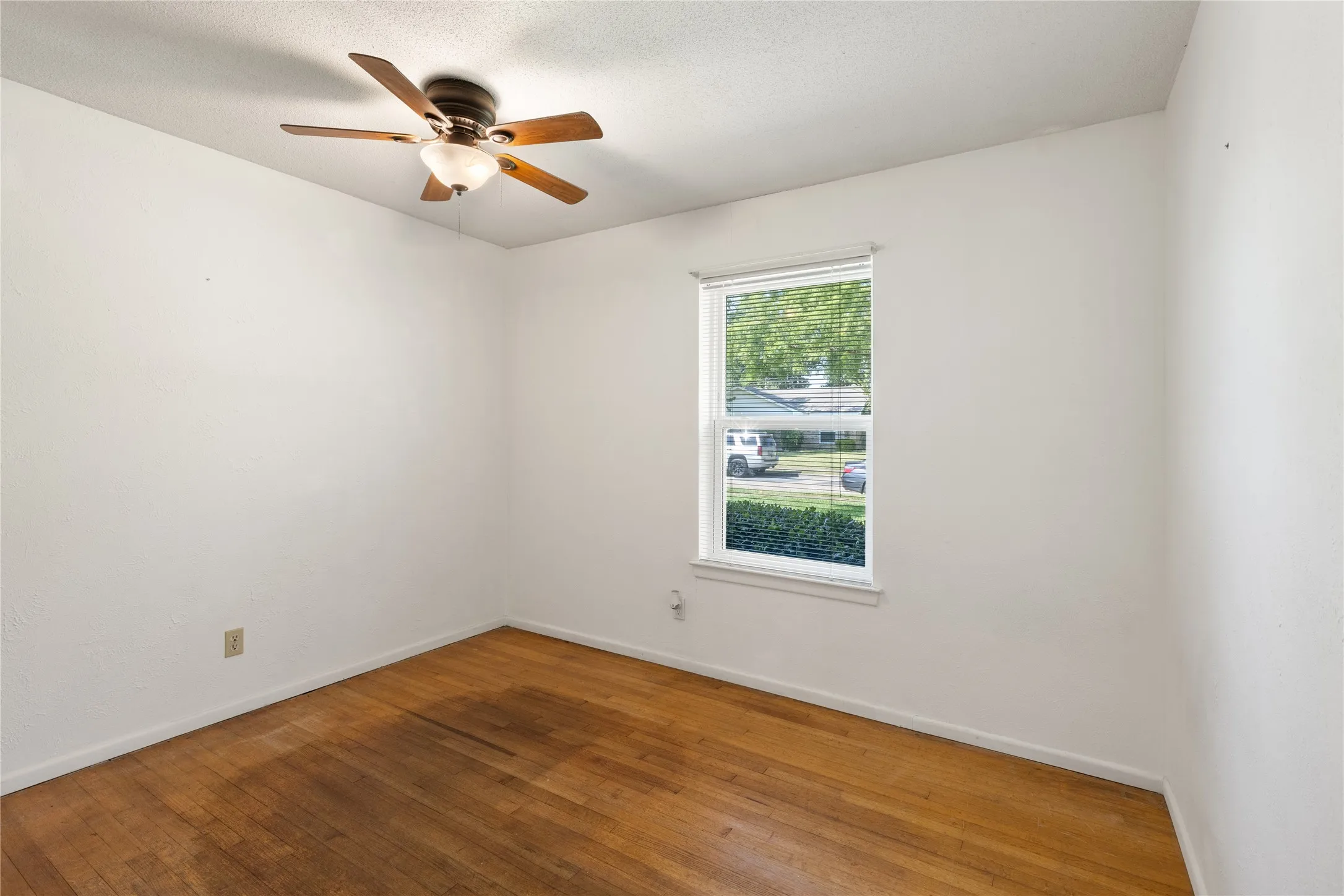 Hardwood flooring, white walls, and a ceiling fan with integrated lighting