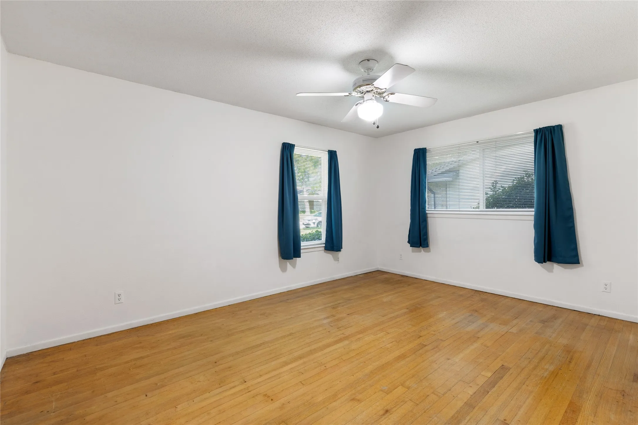 Hardwood flooring, white walls, and a ceiling fan with integrated lighting
