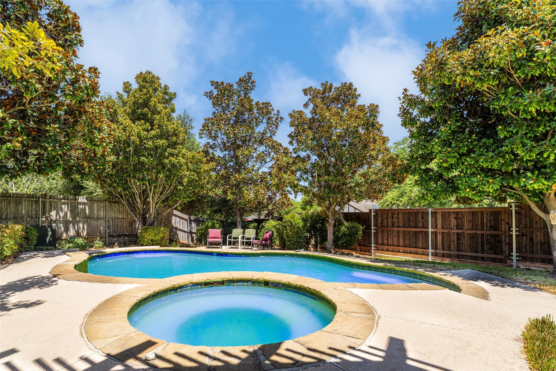 Outdoor swimming pool with integrated spa and surrounding concrete patio