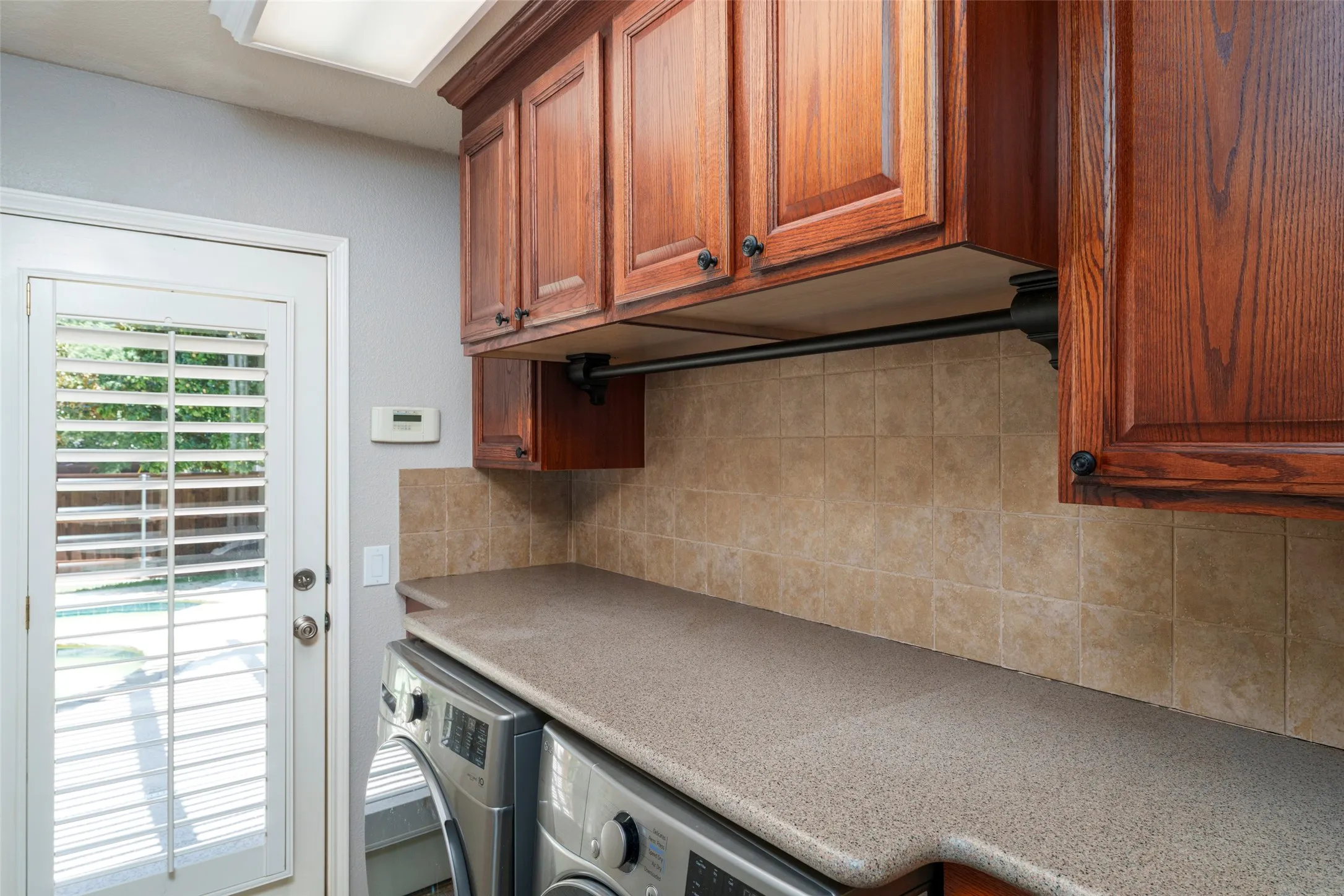 Wood-finish cabinetry, solid surface countertop, tiled backsplash, and a white paneled door