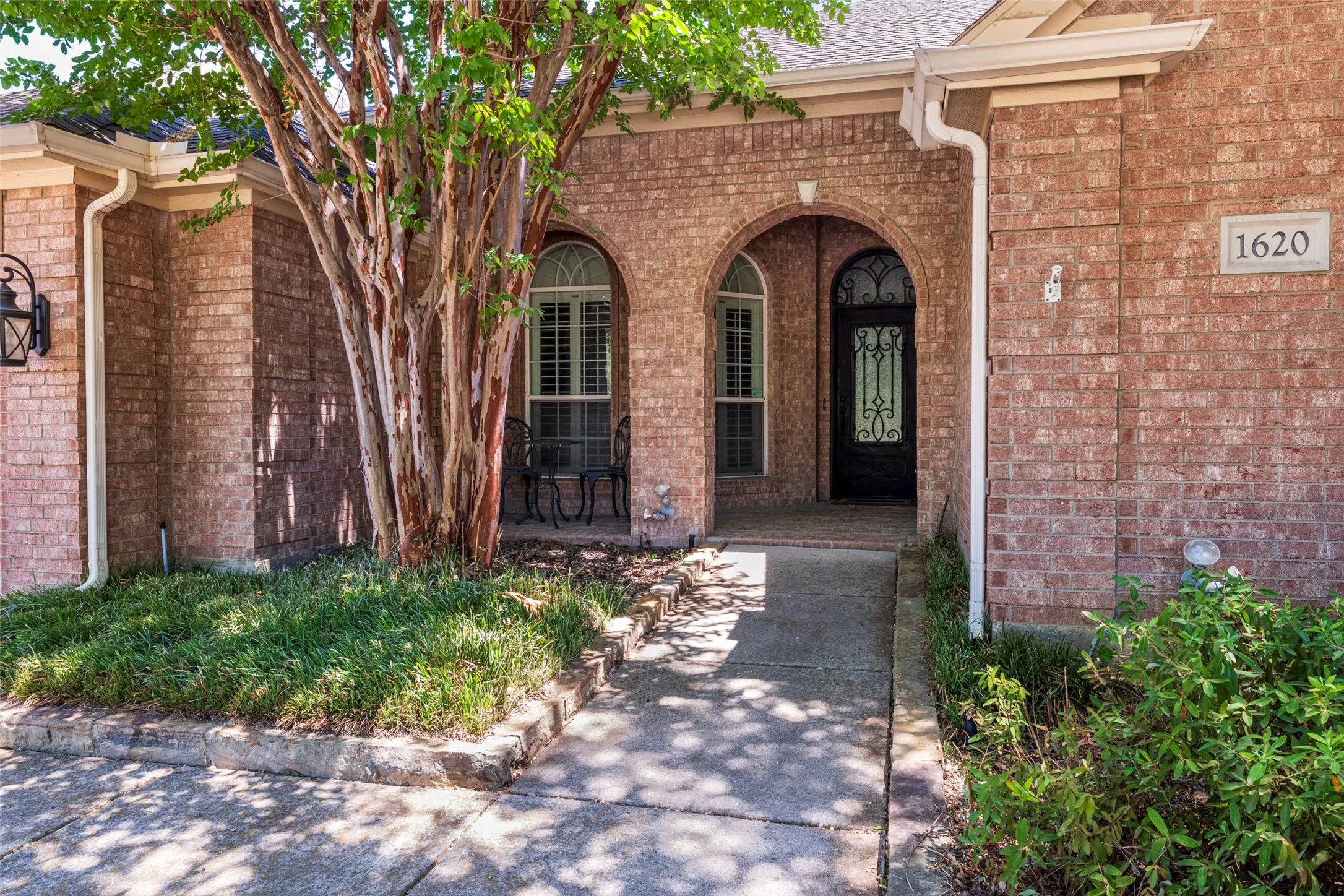 Brick exterior with arched entryways, a decorative glass front door, and a concrete​​‌​​​​‌​​‌‌​‌‌​​​‌‌​‌​‌​‌​​​‌​​ pathway