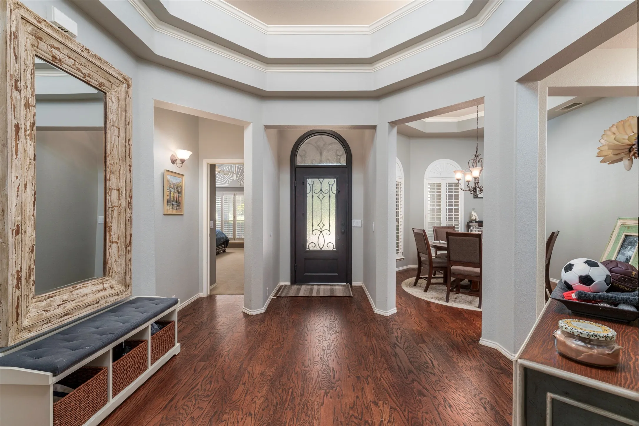 Hardwood-style flooring throughout, an arched front door with decorative glass, and a coffered ceiling detail