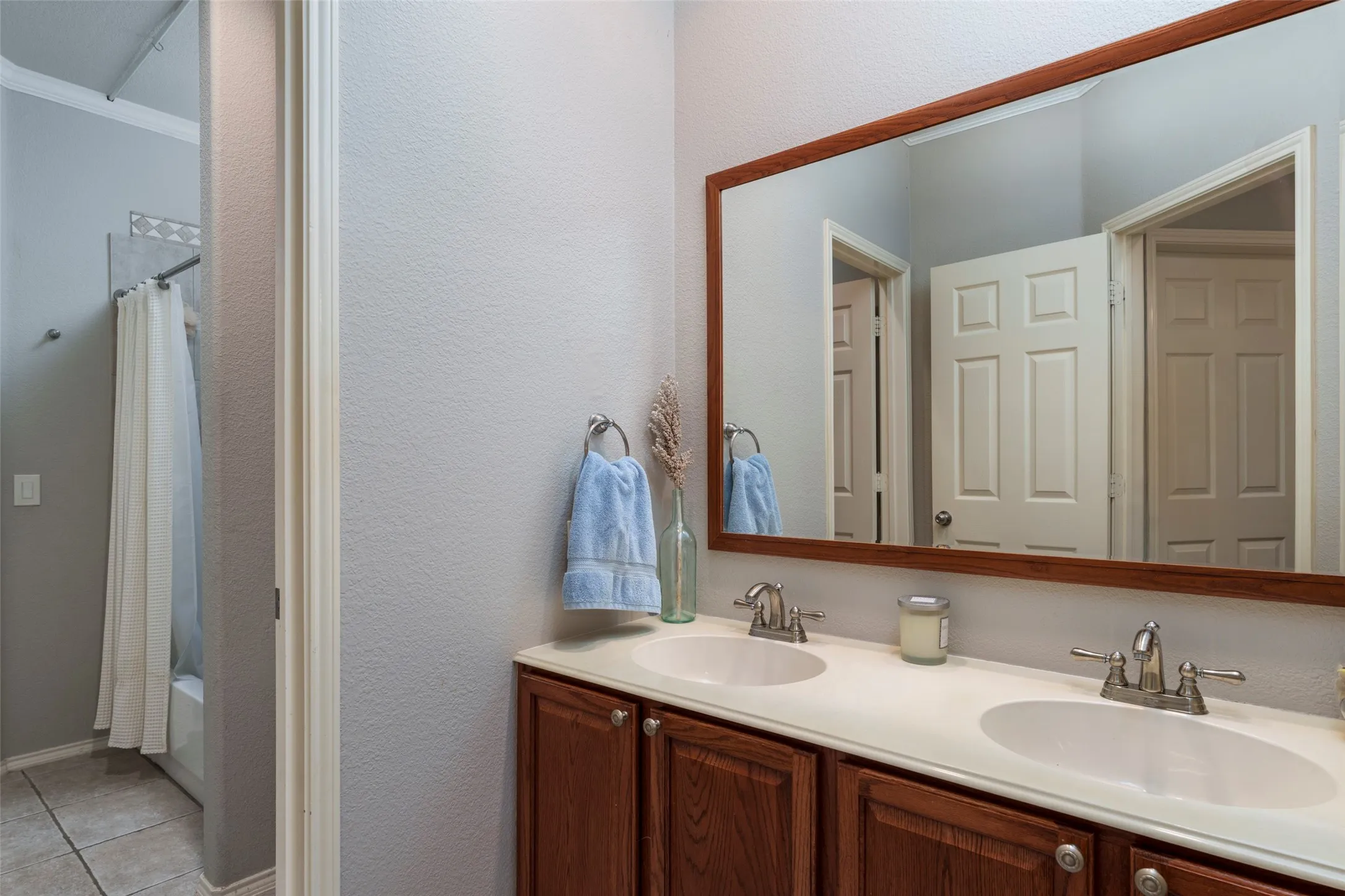 Dual vanity with integrated sinks, wood-finish cabinetry, and a framed mirror