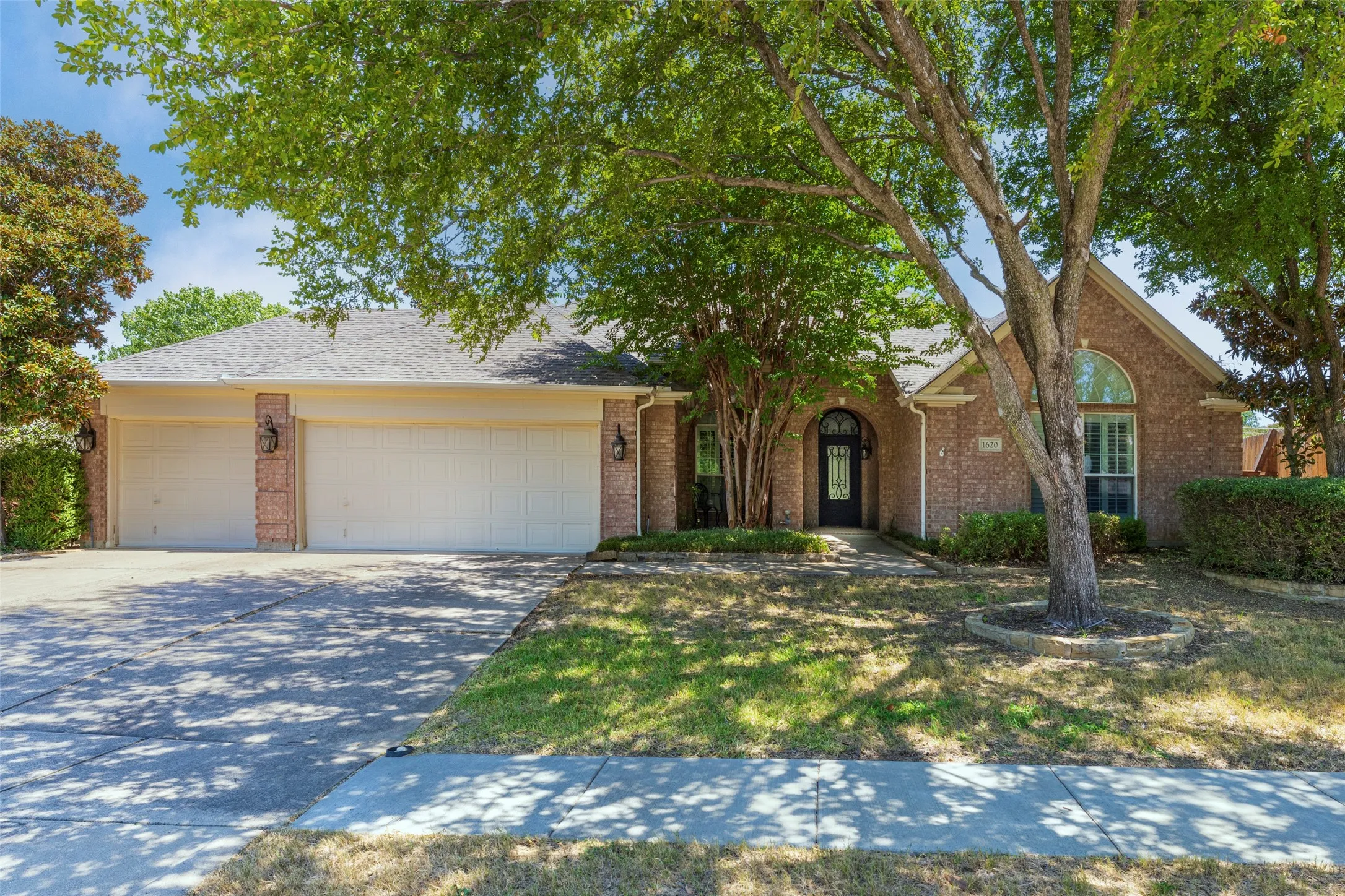 Brick exterior with arched entry, dual garage doors, and an arched window