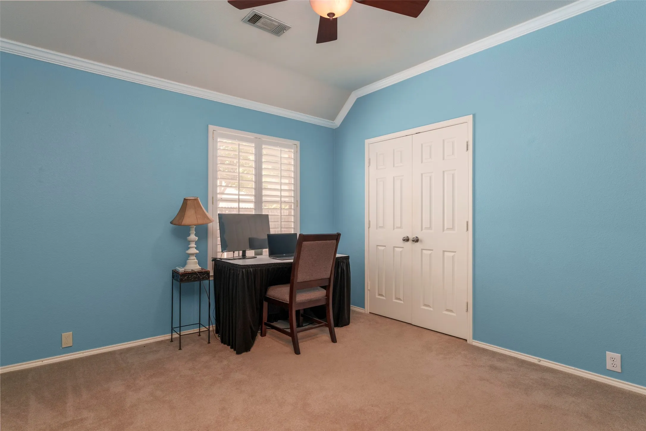 Recessed window with white plantation shutters, white crown molding, vaulted ceiling, and carpeted flooring