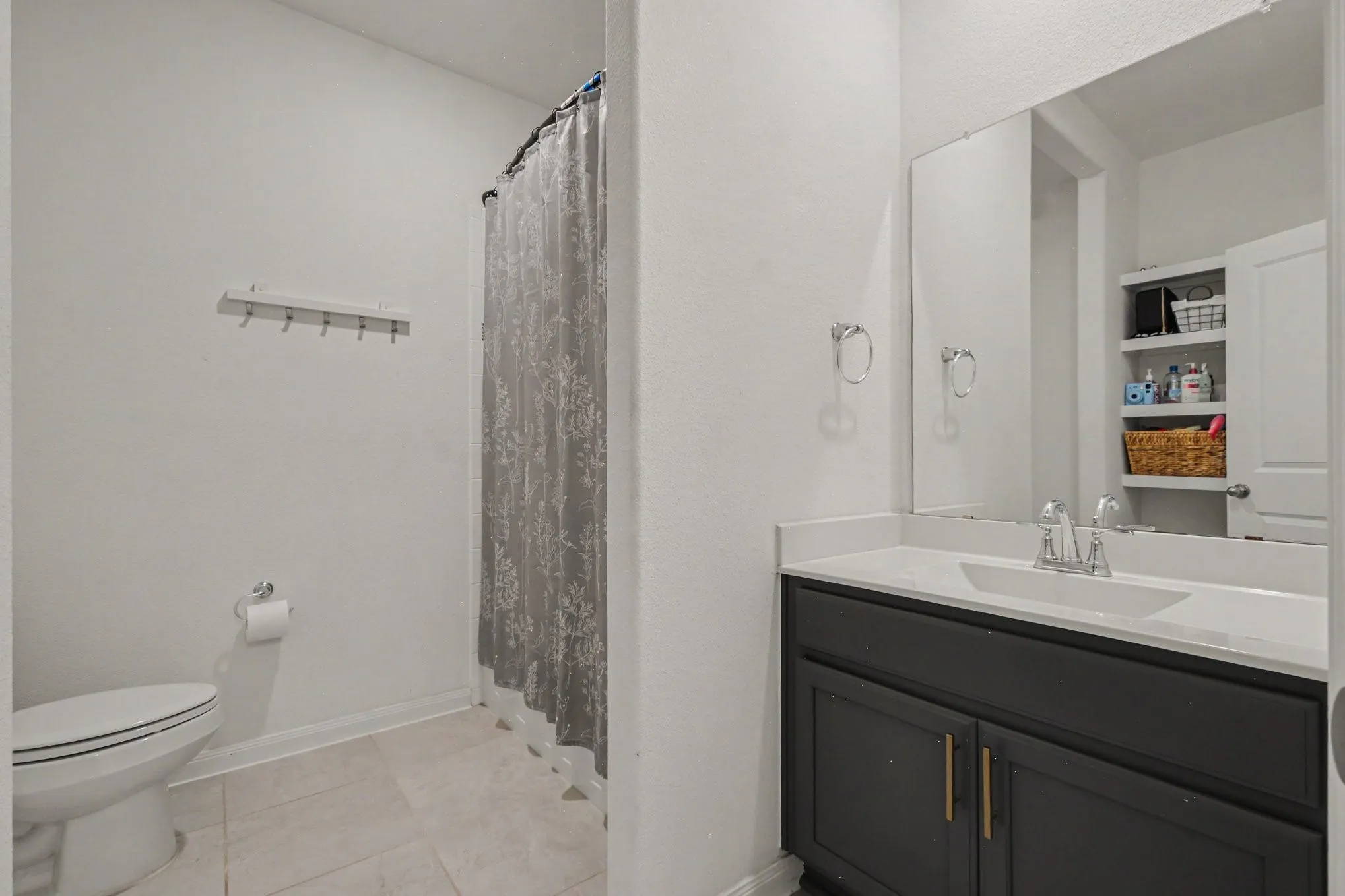 Dark wood vanity with dual gold-finish hardware, white rectangular sink, and light-tone countertop
