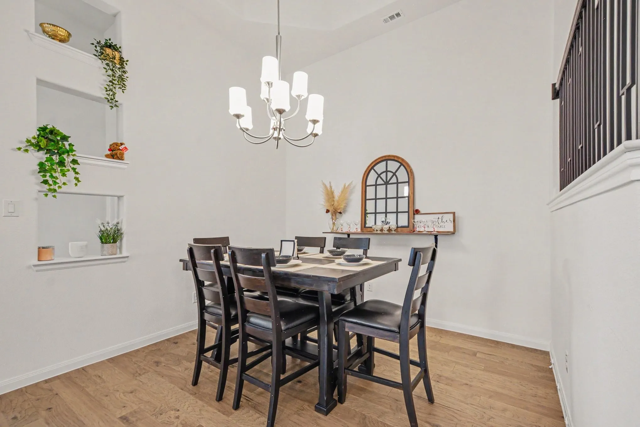 Vaulted ceiling, wood-finish flooring, built-in wall niches, and a chandelier with opaque glass shades