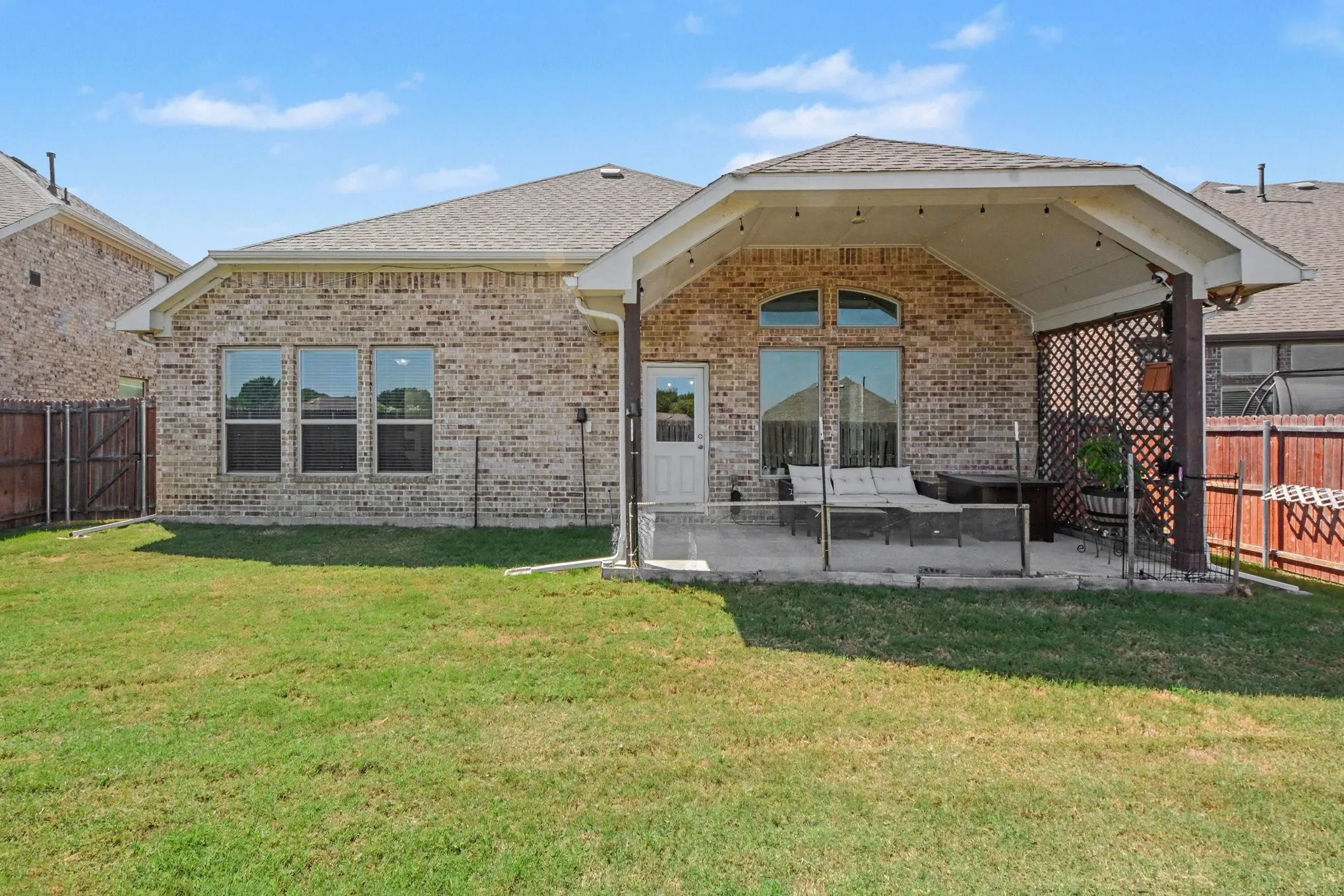 Brick exterior with a covered patio, featuring an arched window and a privacy screen