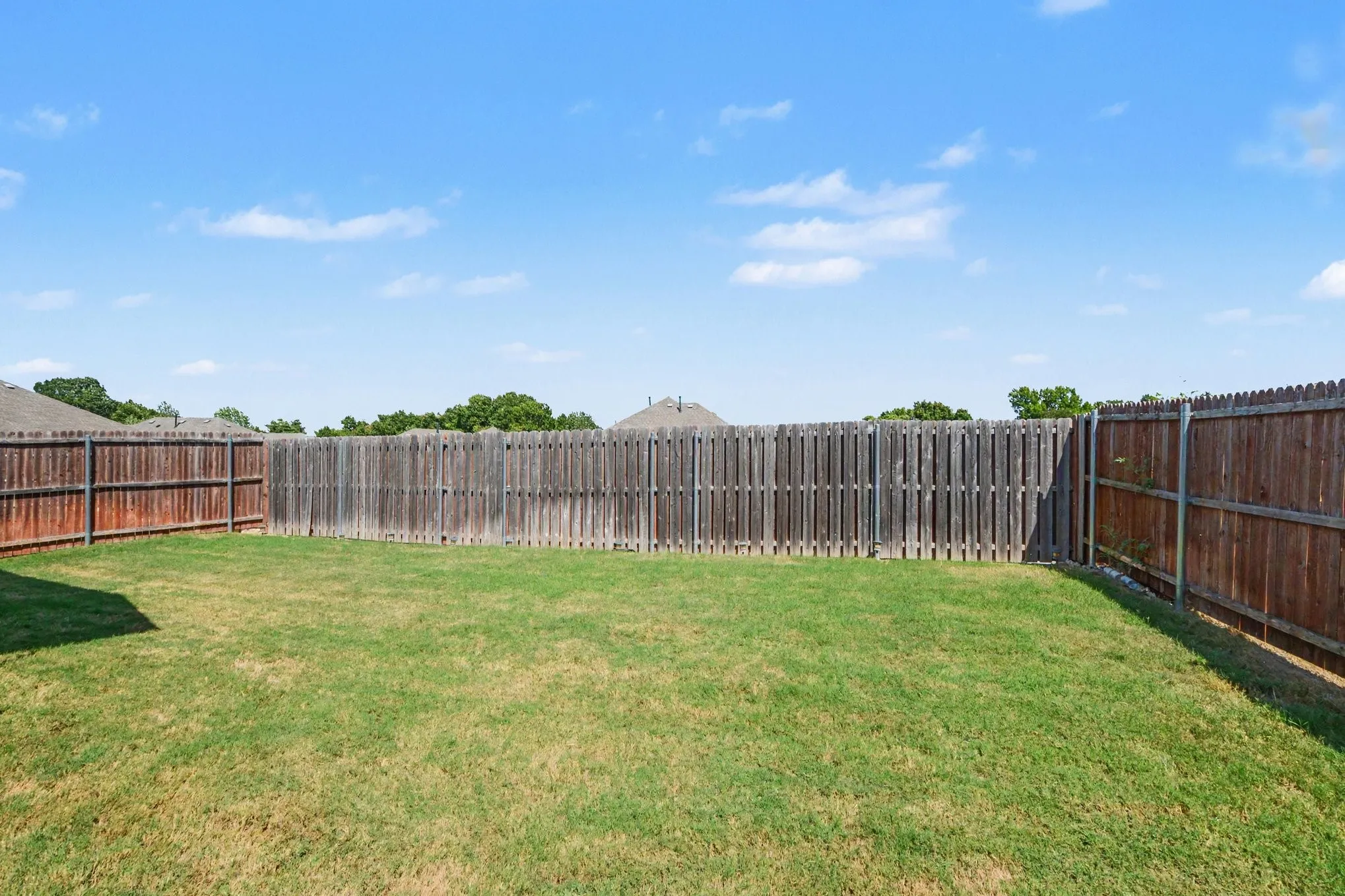 Spacious backyard featuring a manicured lawn and wood privacy fencing