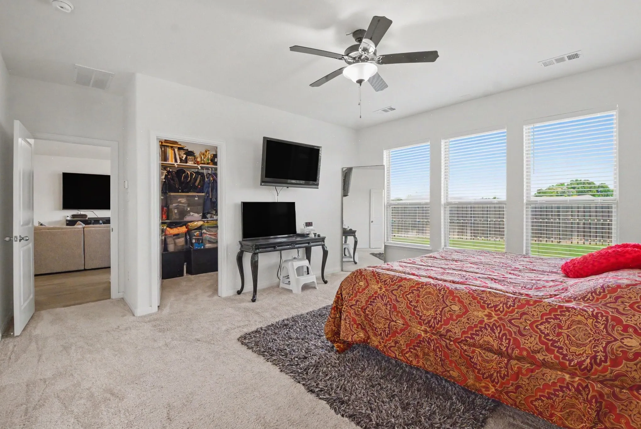 Recessed lighting throughout, ceiling fan with light fixture, multiple windows with horizontal blinds, and a built-in closet with shelving