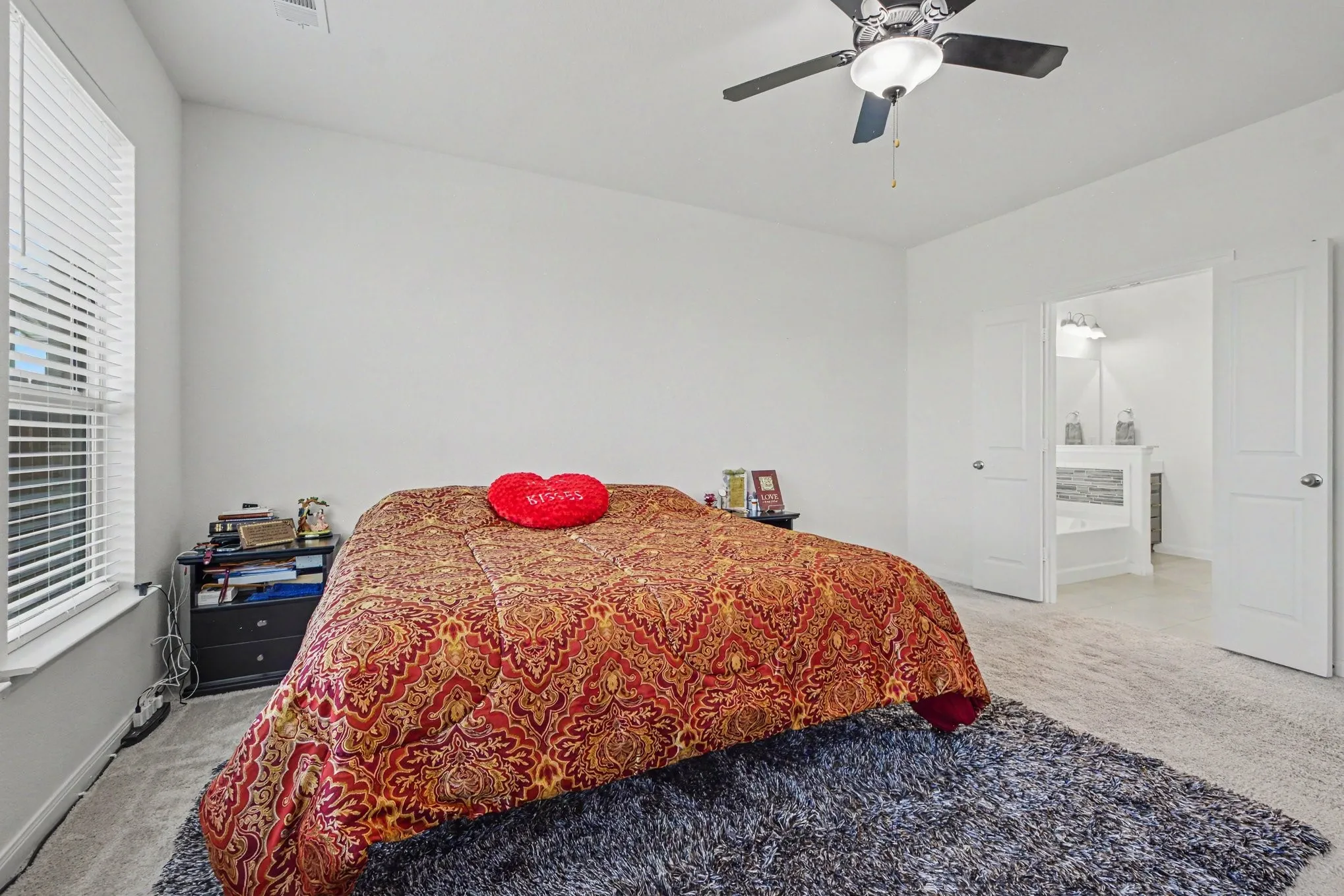 Recessed window with blinds, ceiling fan with integrated lighting, broad wall space, light gray carpeting, and double panel doors