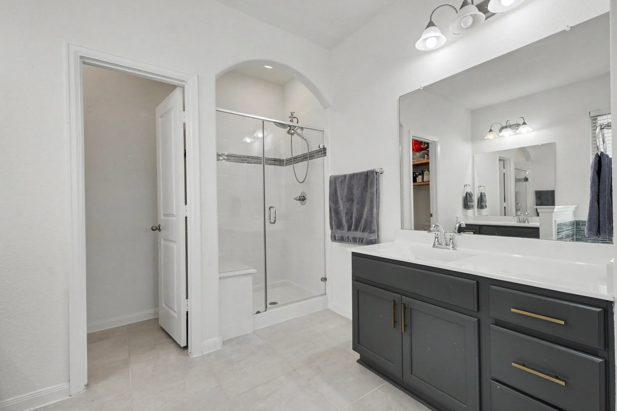 Glass-enclosed shower with a built-in bench and decorative tile band