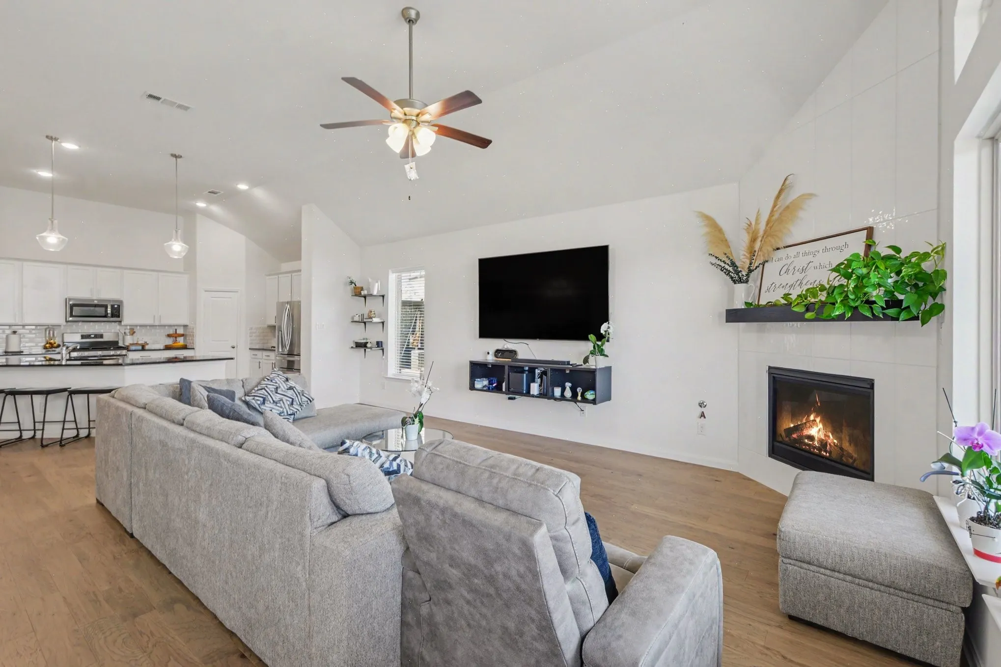 Vaulted ceilings, wood-finish flooring, a contemporary fireplace, and a kitchen featuring pendant lighting and a breakfast bar