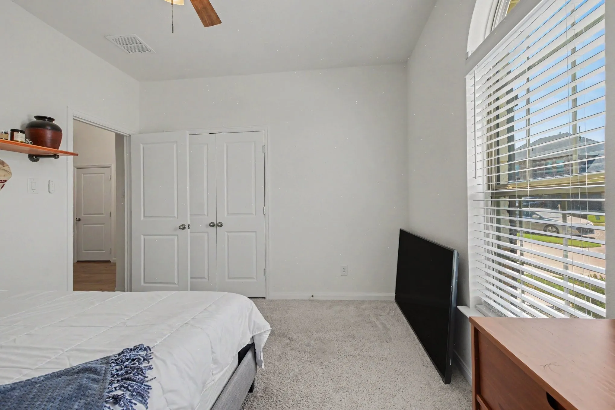 Arched window with blinds, dual closet doors with brushed nickel hardware, and a ceiling fan