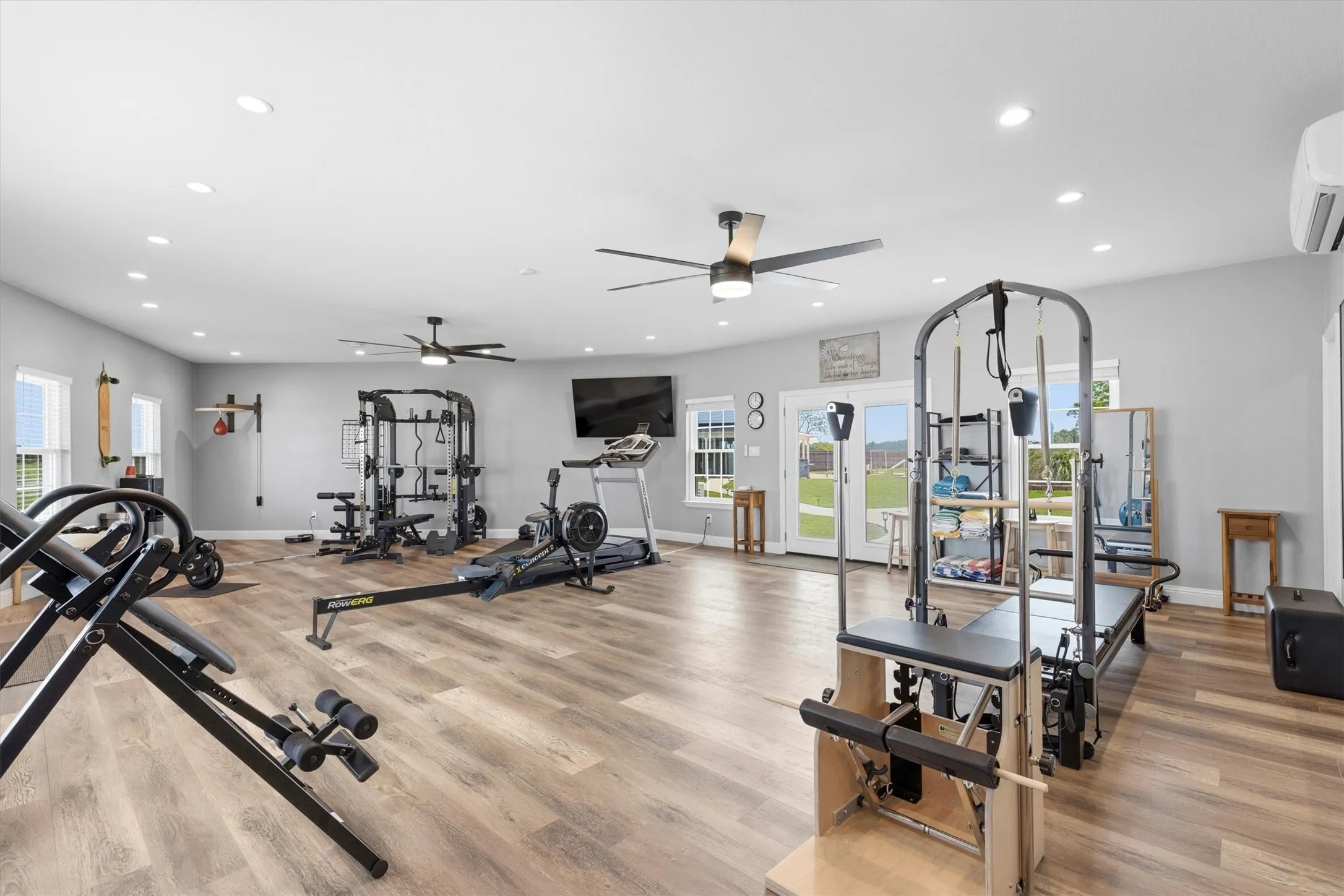 Spacious room featuring wood-finish flooring, recessed lighting, ceiling fans, and double French doors to the exterior