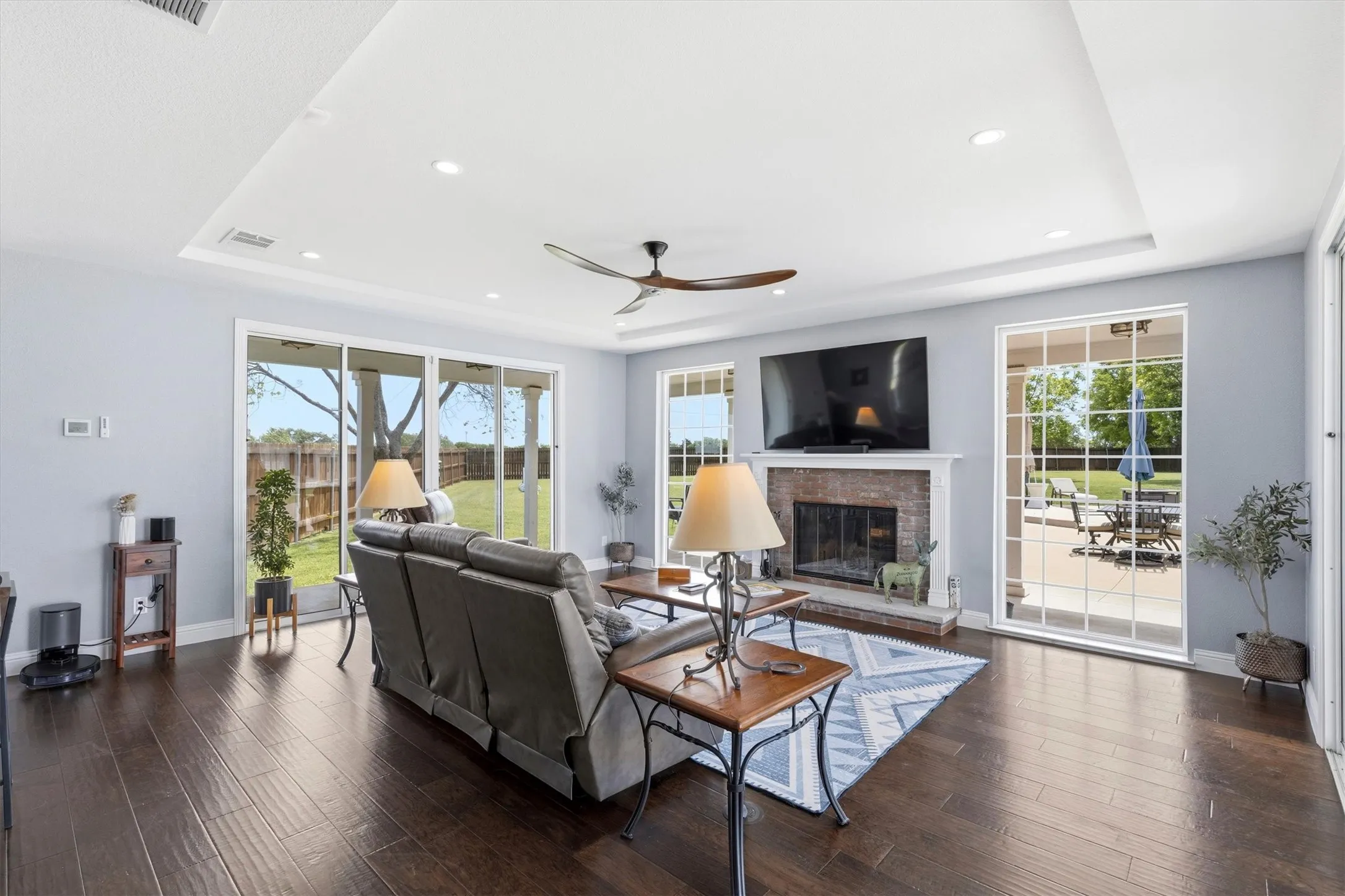 Recessed lighting illuminates the tray ceiling, complementing the wood-finish flooring