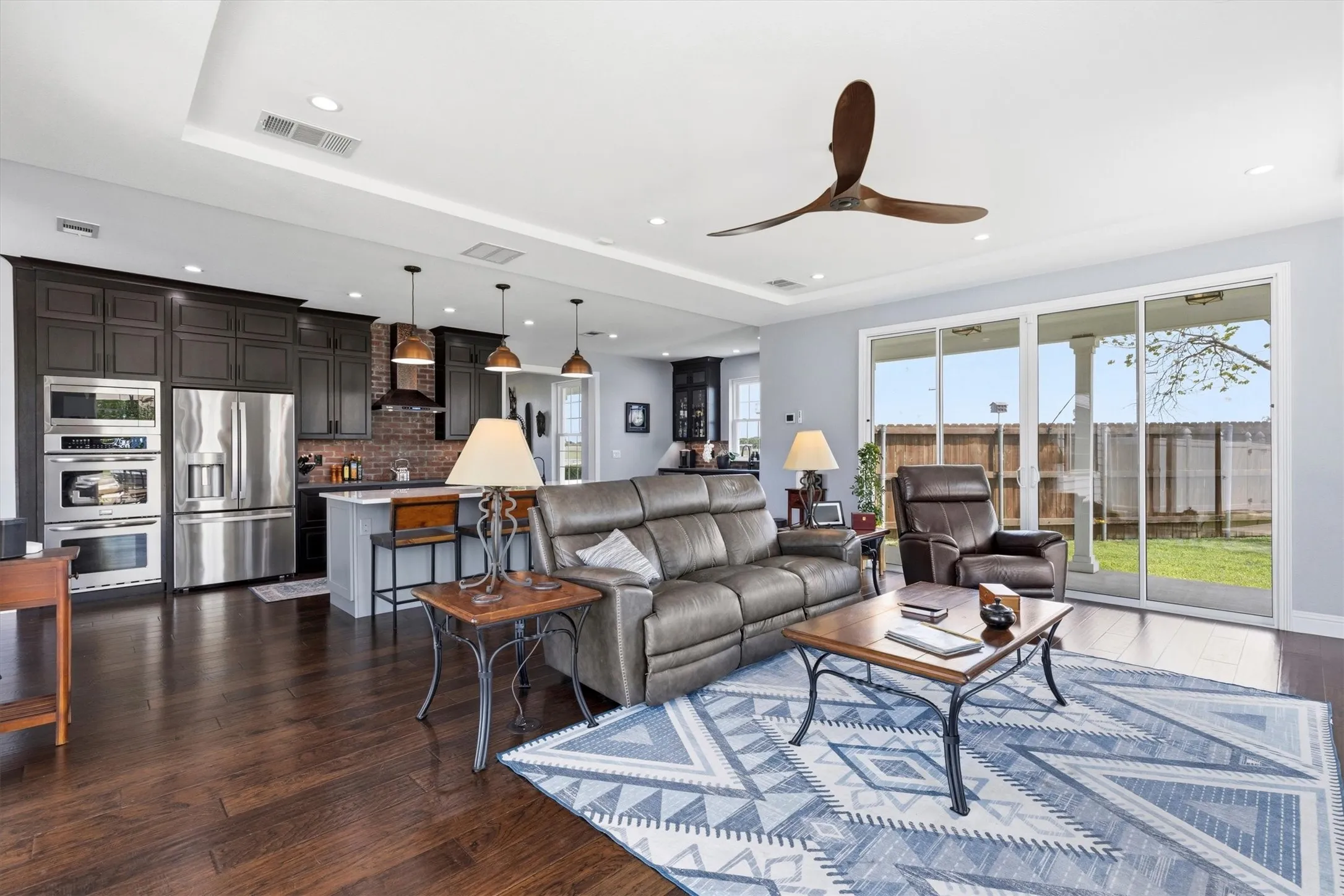 Expansive living area with wood-finish flooring, recessed lighting, and a modern ceiling fan