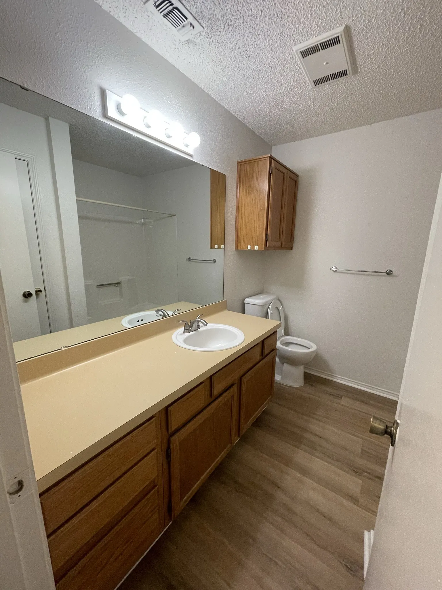 Long vanity with integrated sink, wood-finish cabinetry, and a full-width mirror
