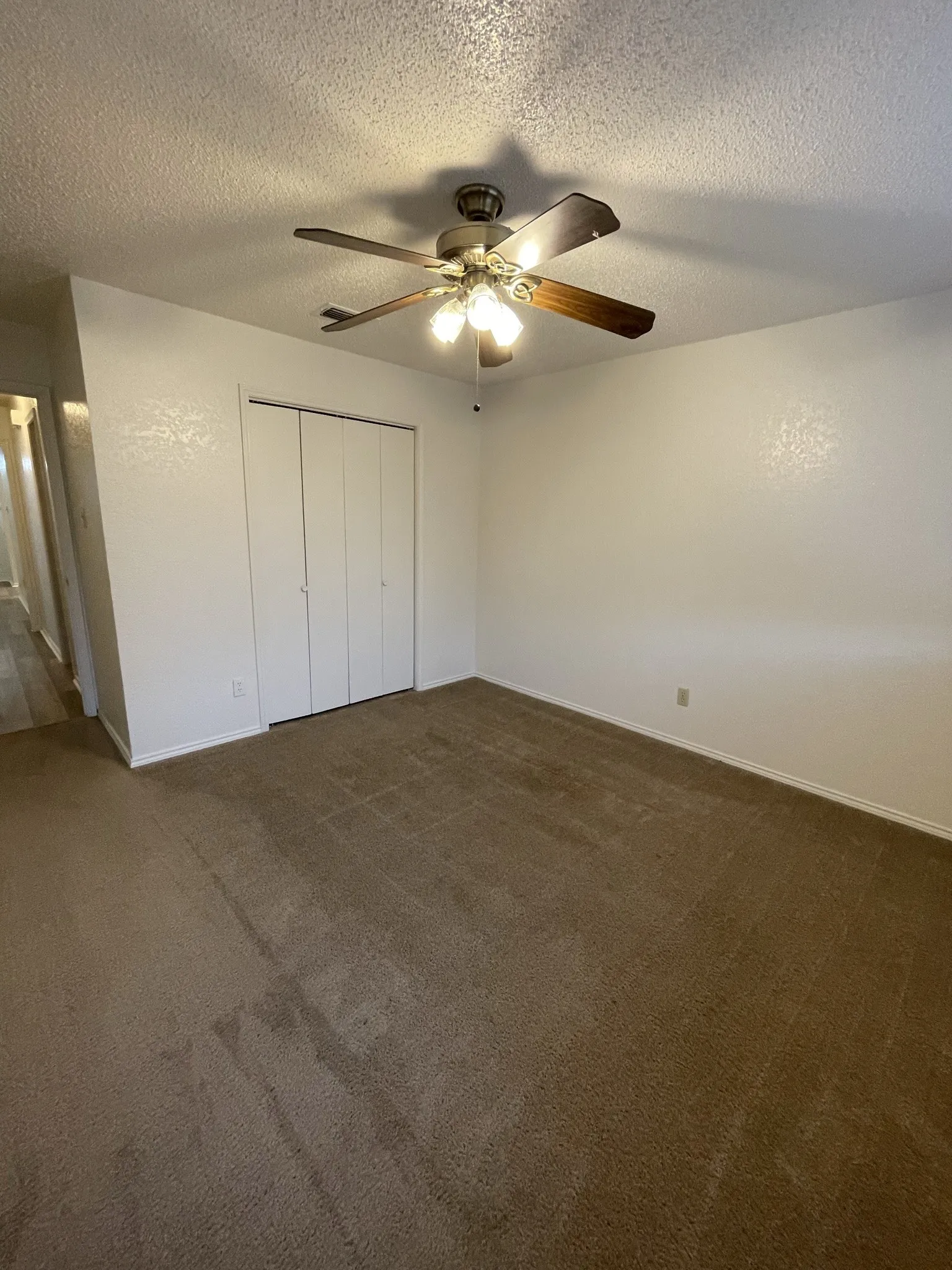 Neutral-toned carpeting, ceiling fan with integrated lighting, bi-fold closet doors, and painted walls