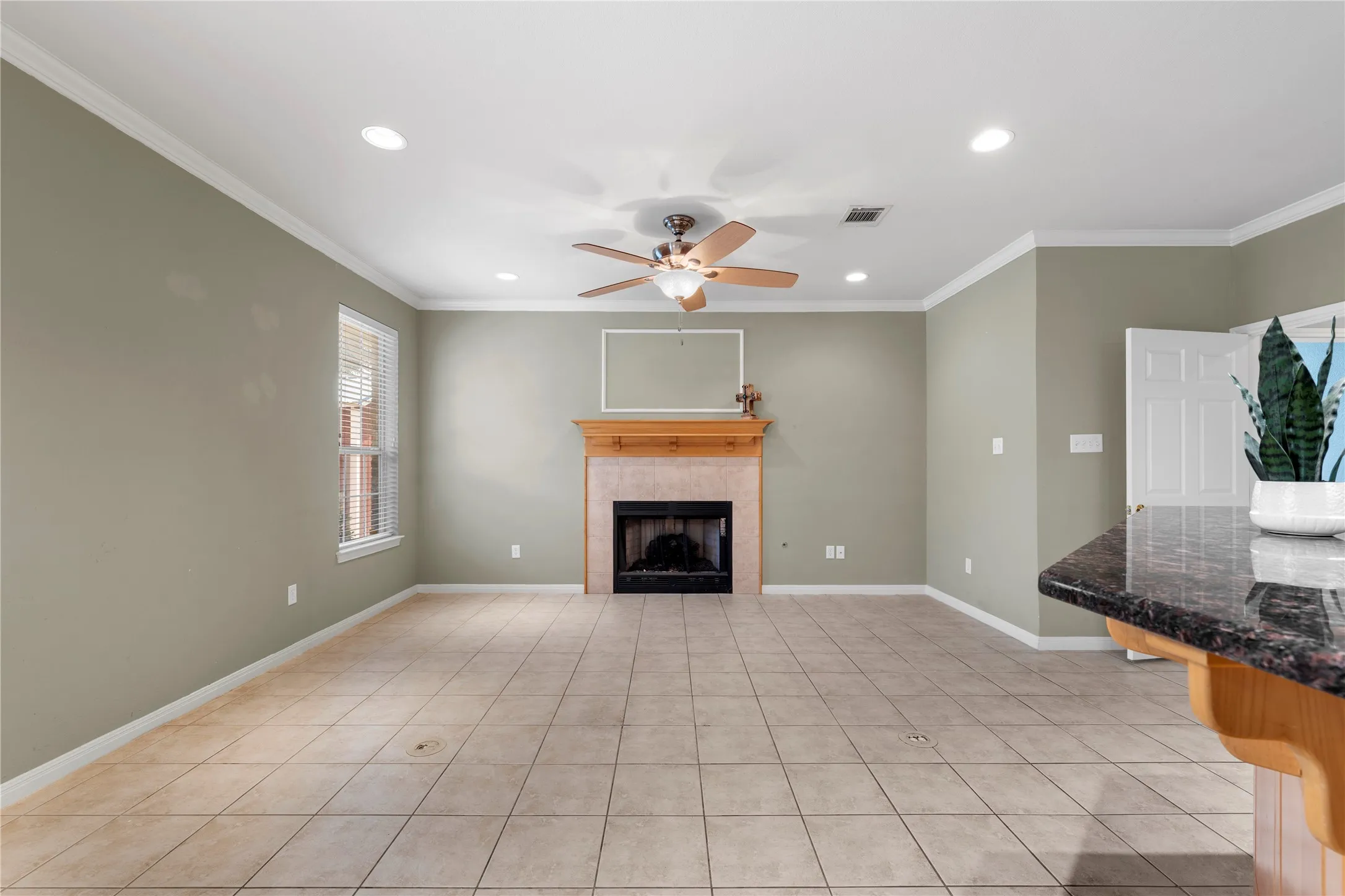 Tile flooring, fireplace with wood mantel, recessed lighting, ceiling fan, and crown molding