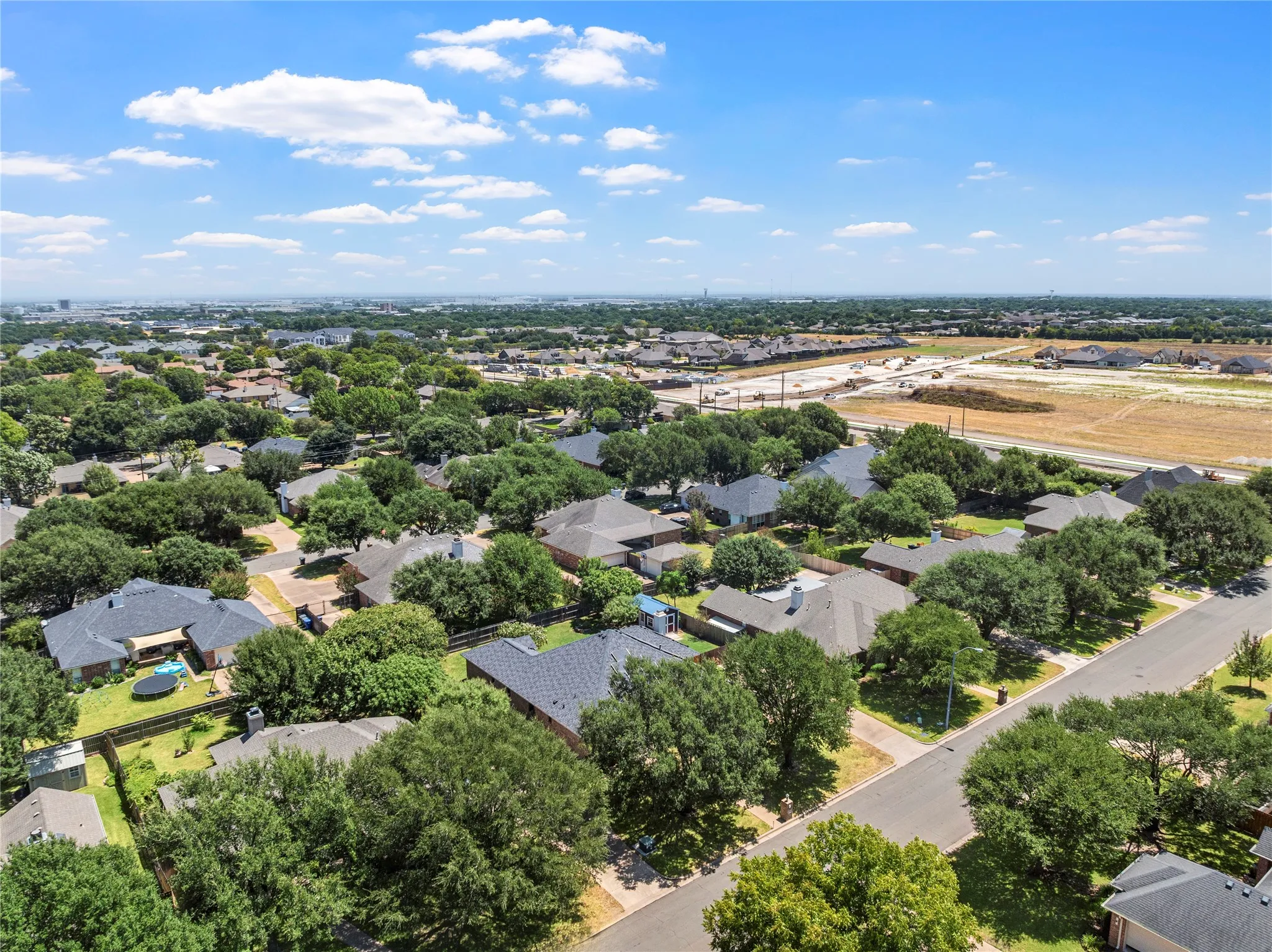 Residential area with extensive tree canopy, paved roads, and visible rooftops