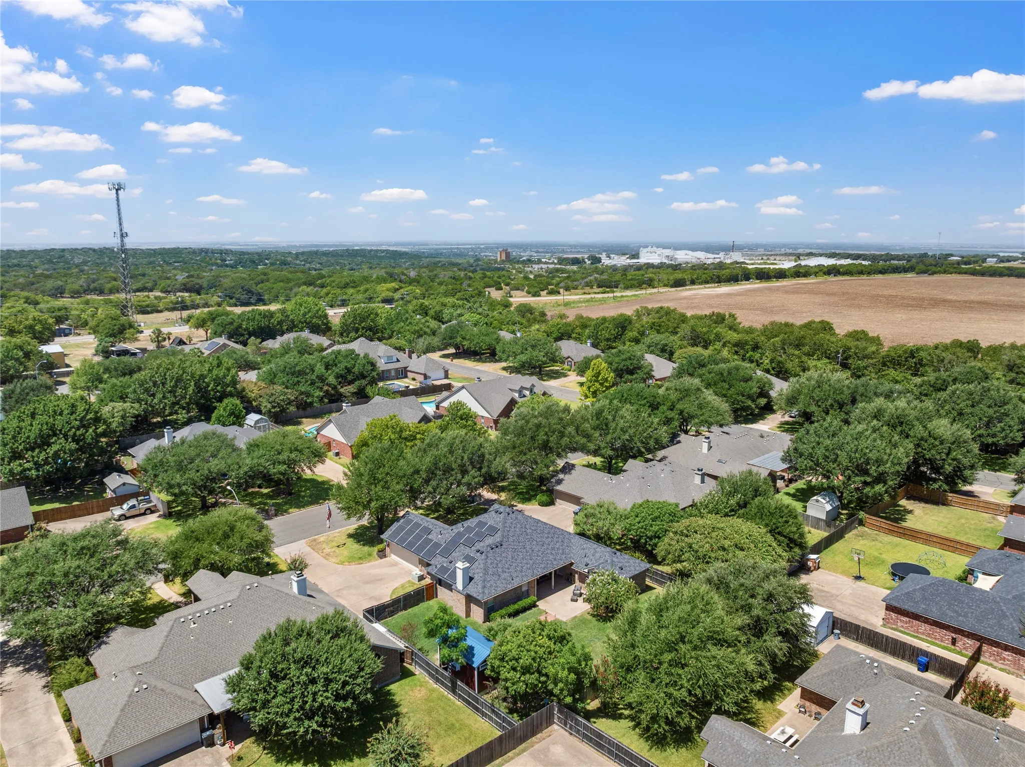 Expansive neighborhood featuring mature trees, residential properties, and a large open field