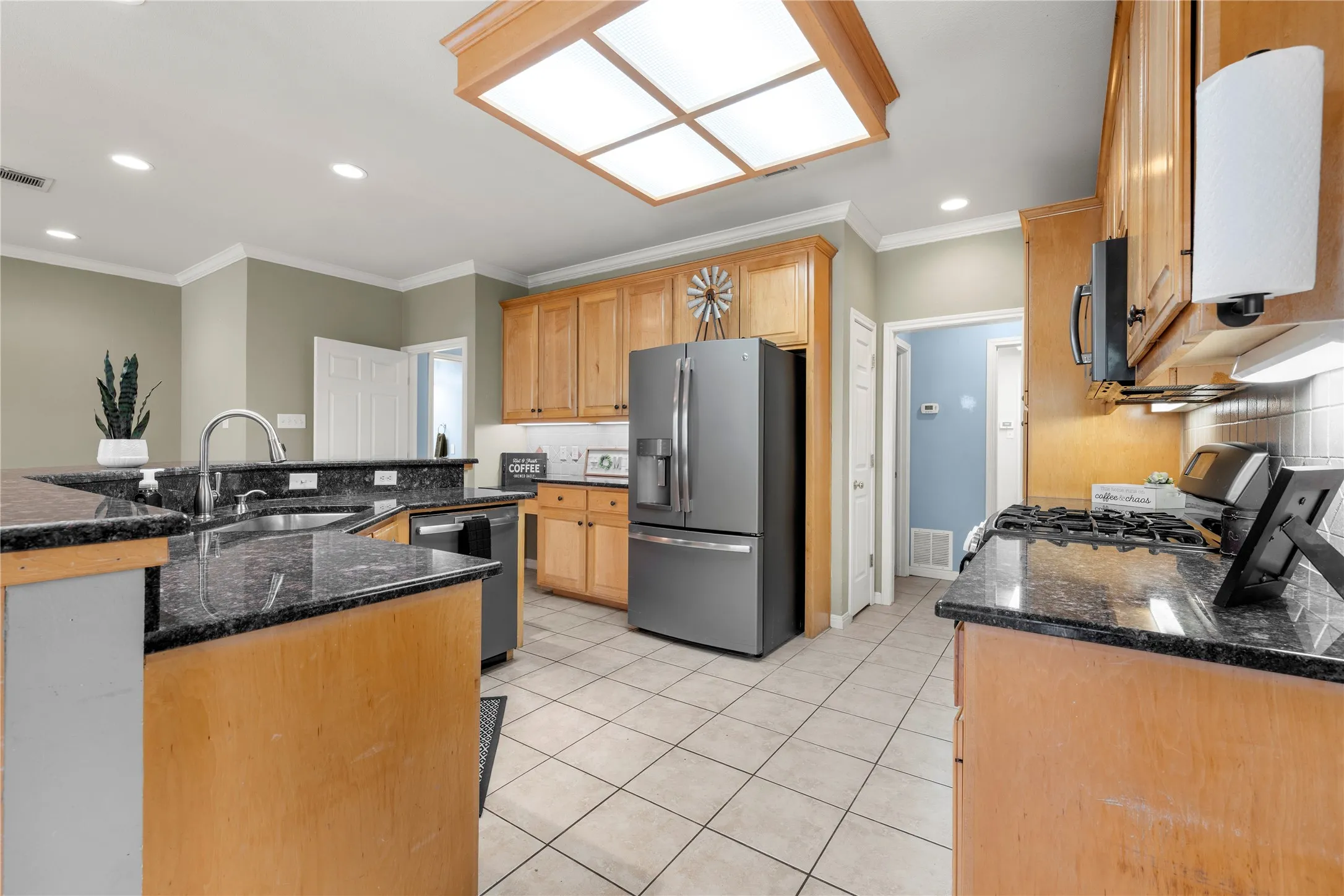 Kitchen featuring granite countertops, wood cabinetry, stainless steel appliances, and tile flooring