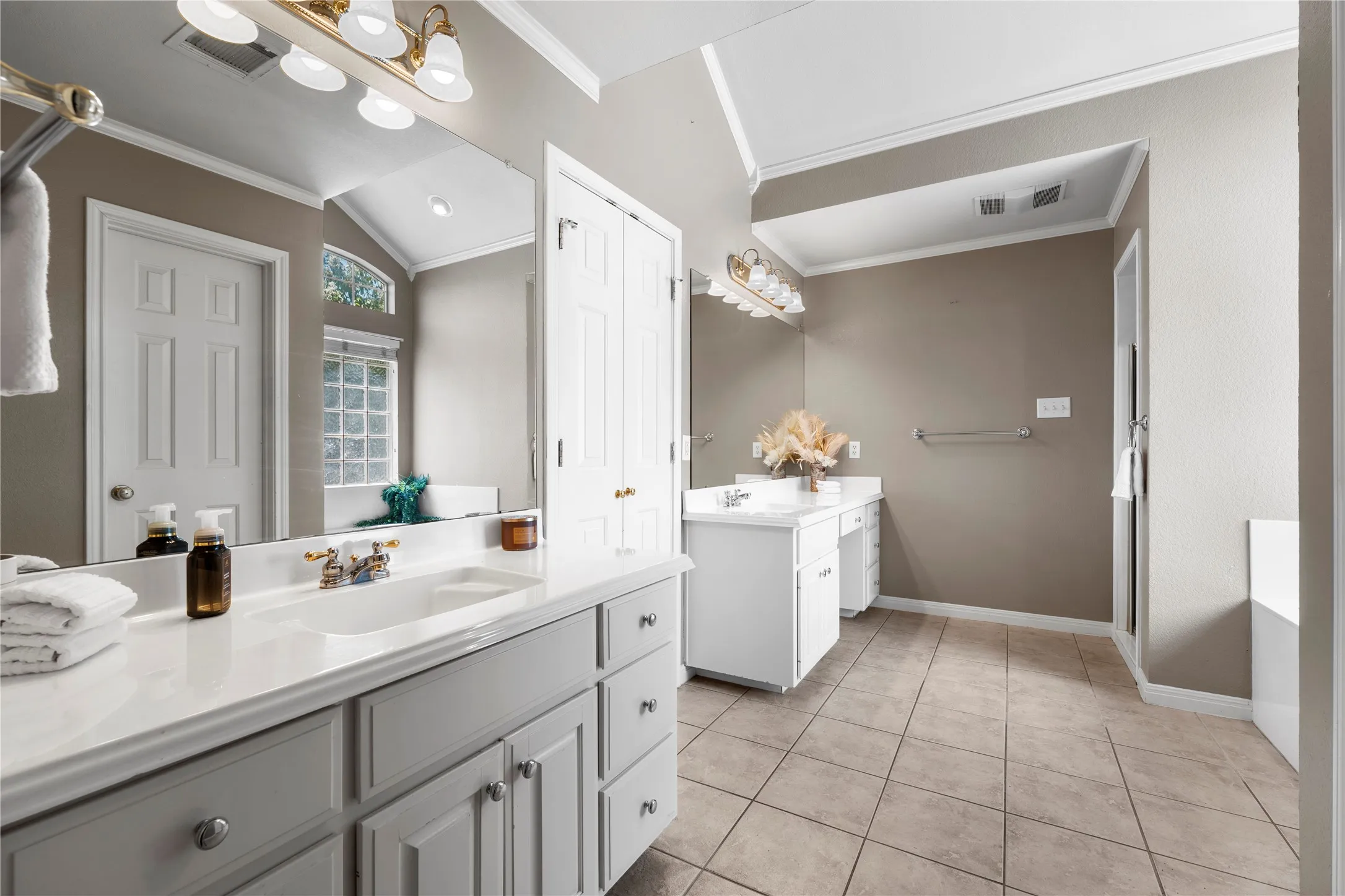 Dual vanity with white countertops, integrated sinks, and brass-finish fixtures