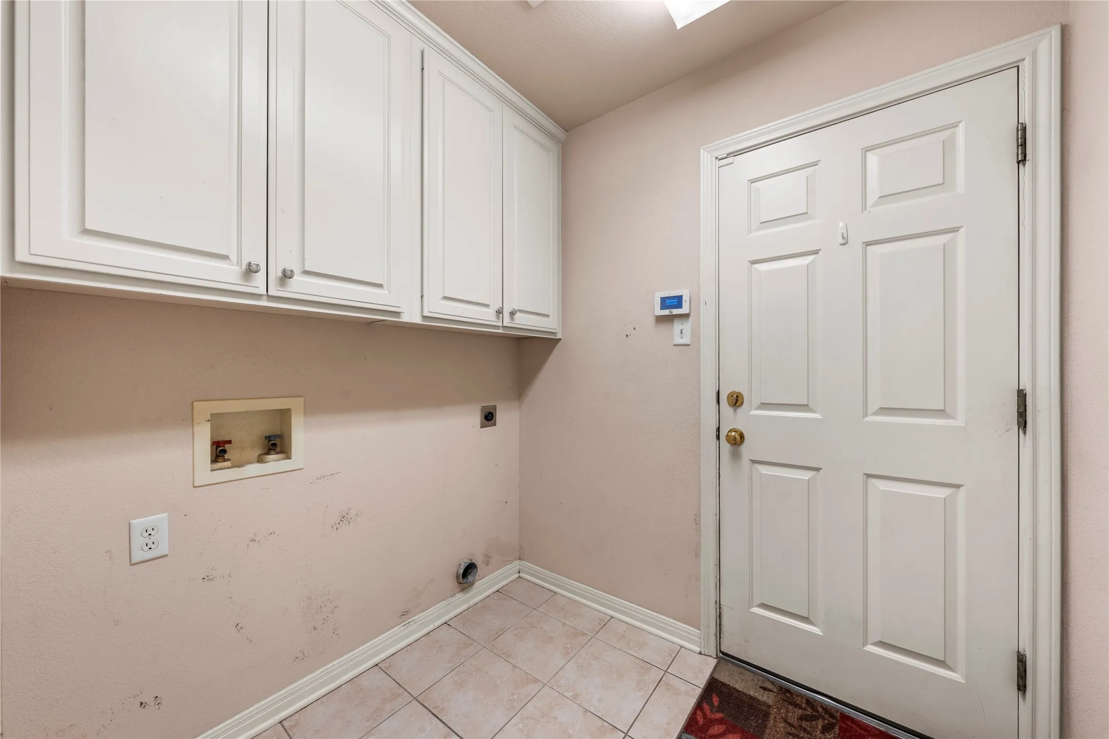 White paneled door, built-in upper cabinetry with silver-tone hardware, and light-toned tile flooring